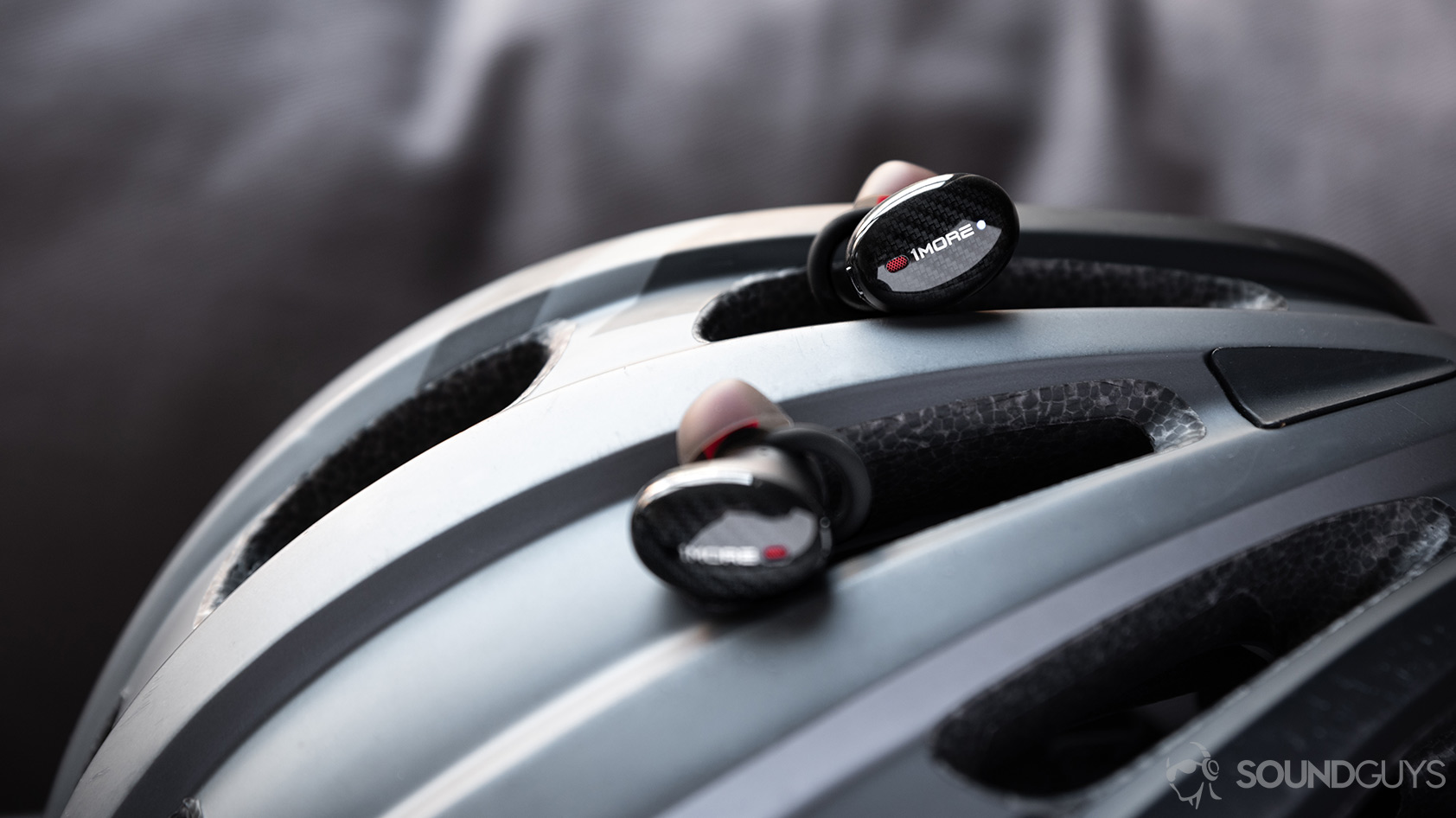 1More True Wireless ANC-earbuds bike helmet The 1More True Wireless ANC earbuds atop a grey bike helmet.