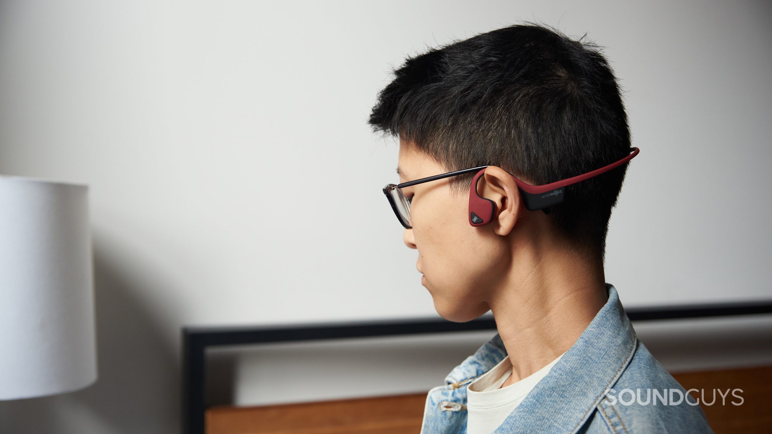 AfterShokz Air bone conduction headphones person wears head turn 2 A person wears the AfterShokz Air bone conduction headphones with their head turned away from the camera.
