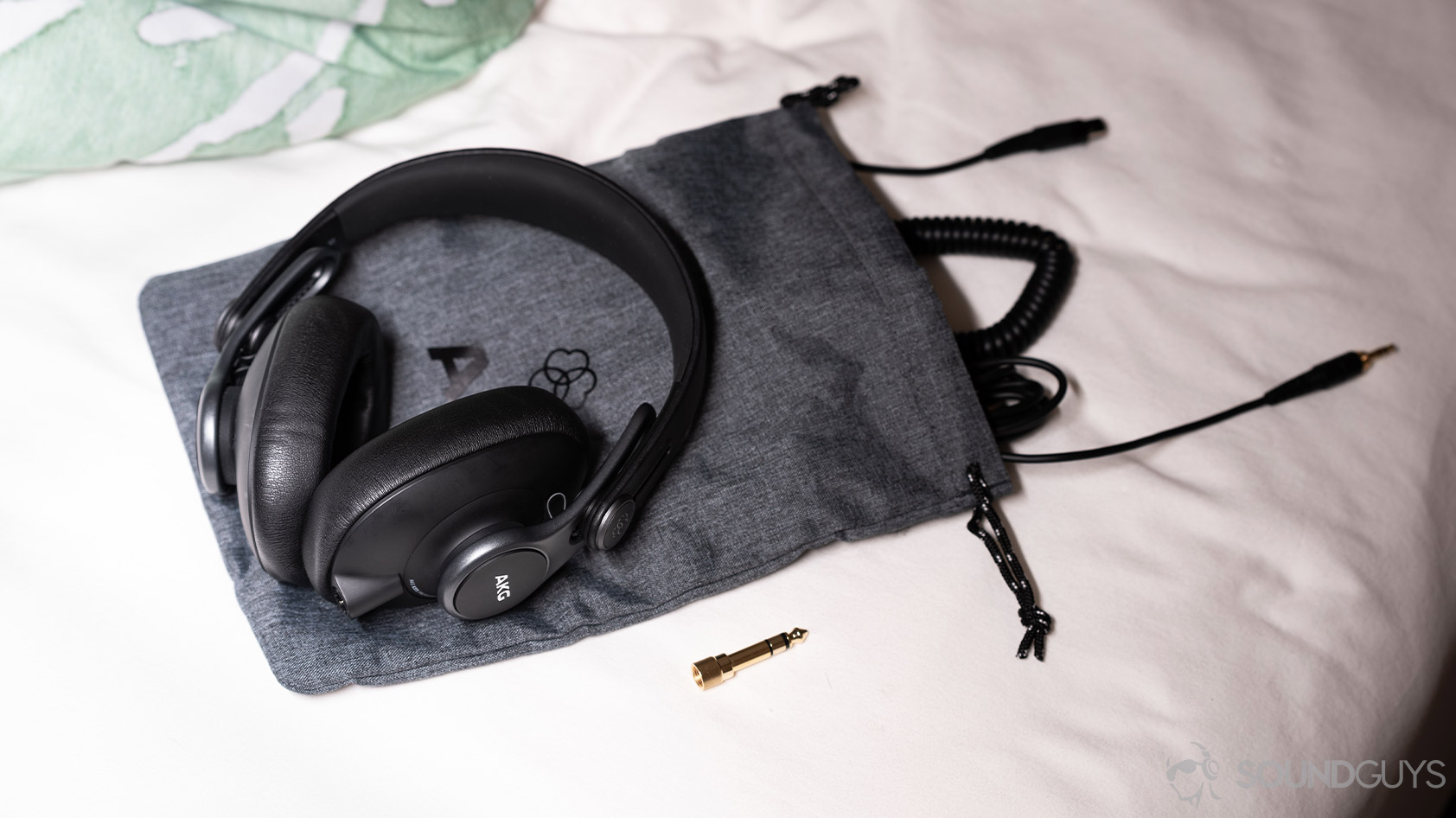 AKG K371-over ear wired headphones cables adapter A picture of the AKG K371 wired over-ear headphones on the included drawstring carrying pouch with the included cables.