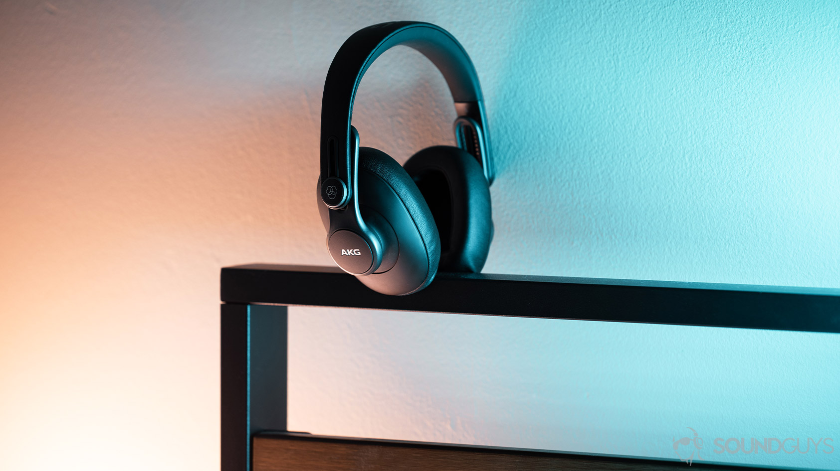 AKG K371-over ear wired headphones hero The AKG K371 wired over-ear headphones on an iron bedrame lit by blue and orange lights.