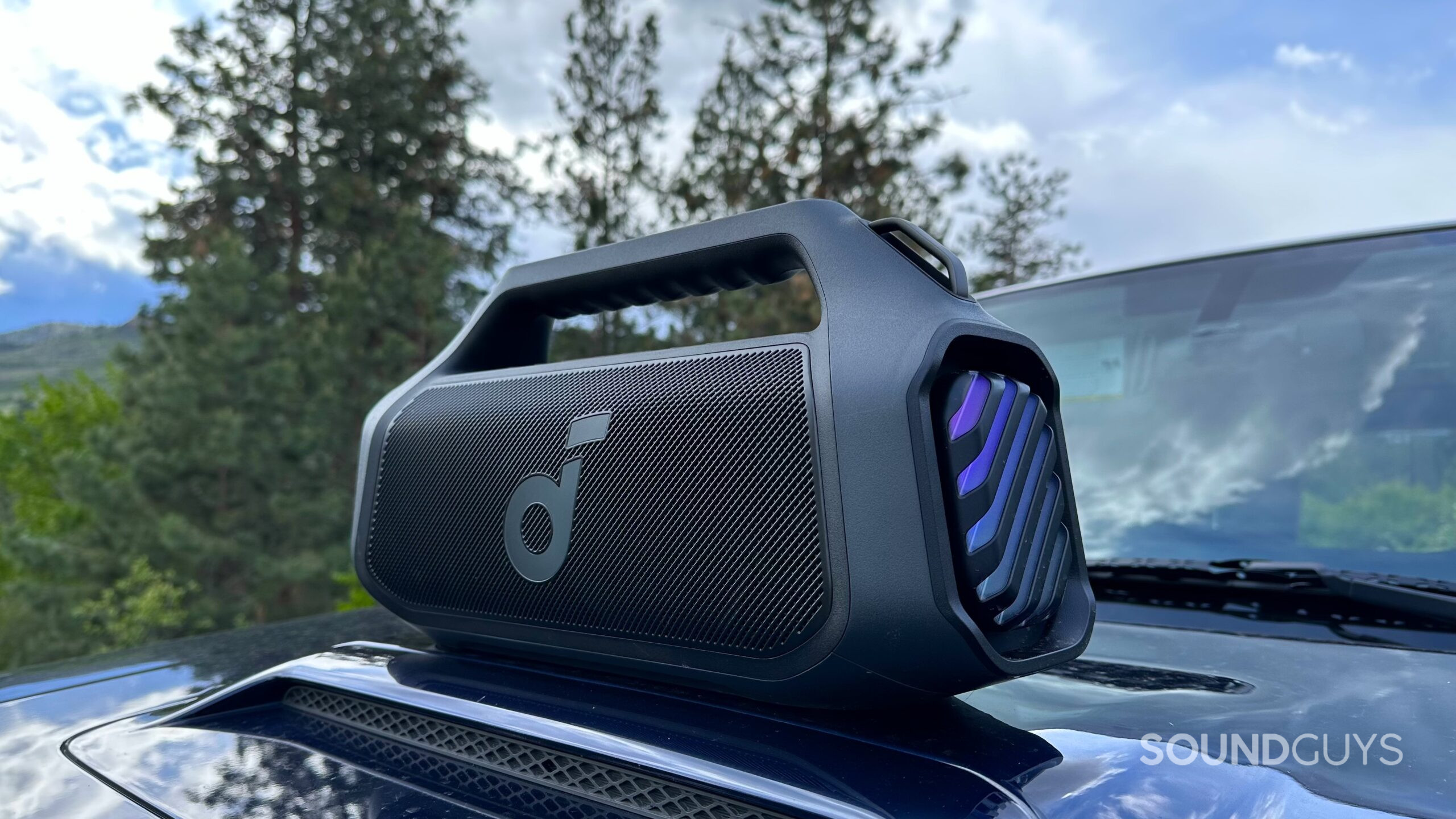 Anker Soundcore Boom 2 Plus 2 An Anker Soundcore Boom 2 Plus placed on top of an automobile hood, angled towards the camera