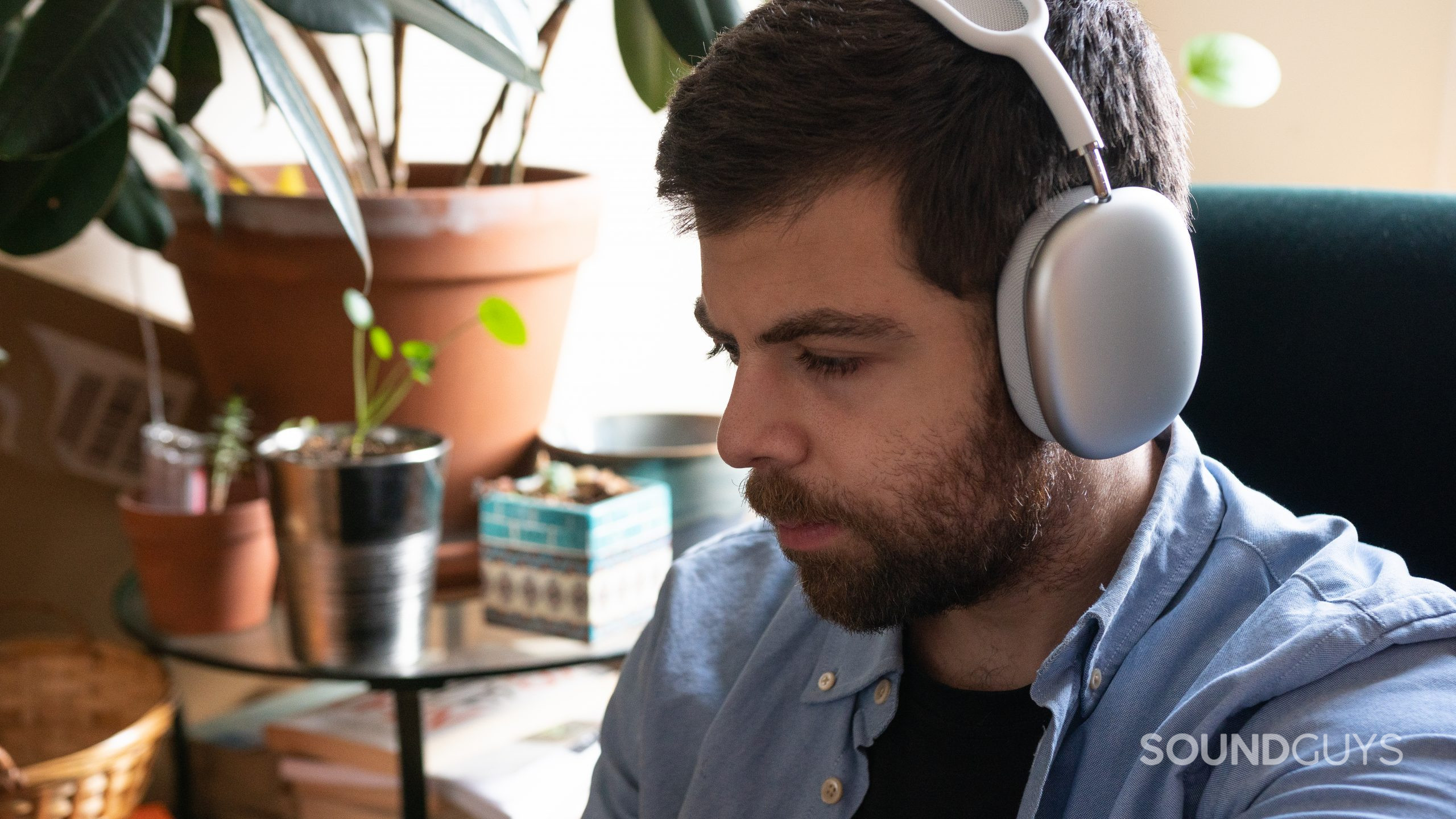Apple AirPods Max on-ear Man wearing the white Apple AirPods Max while sitting in green chair.