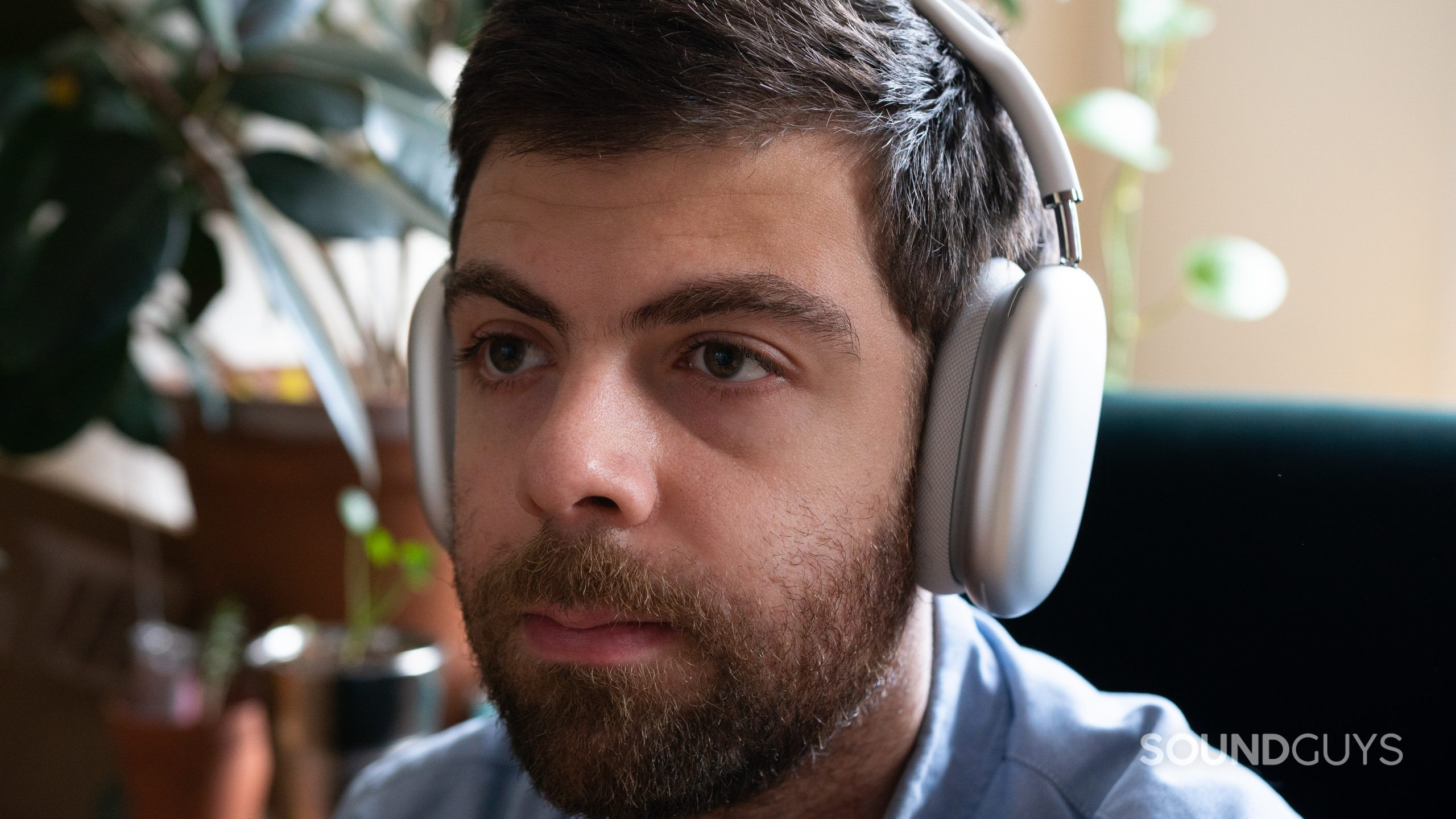 Apple AirPods Max straight-on. Man wearing white Apple AirPods Max looking straight.