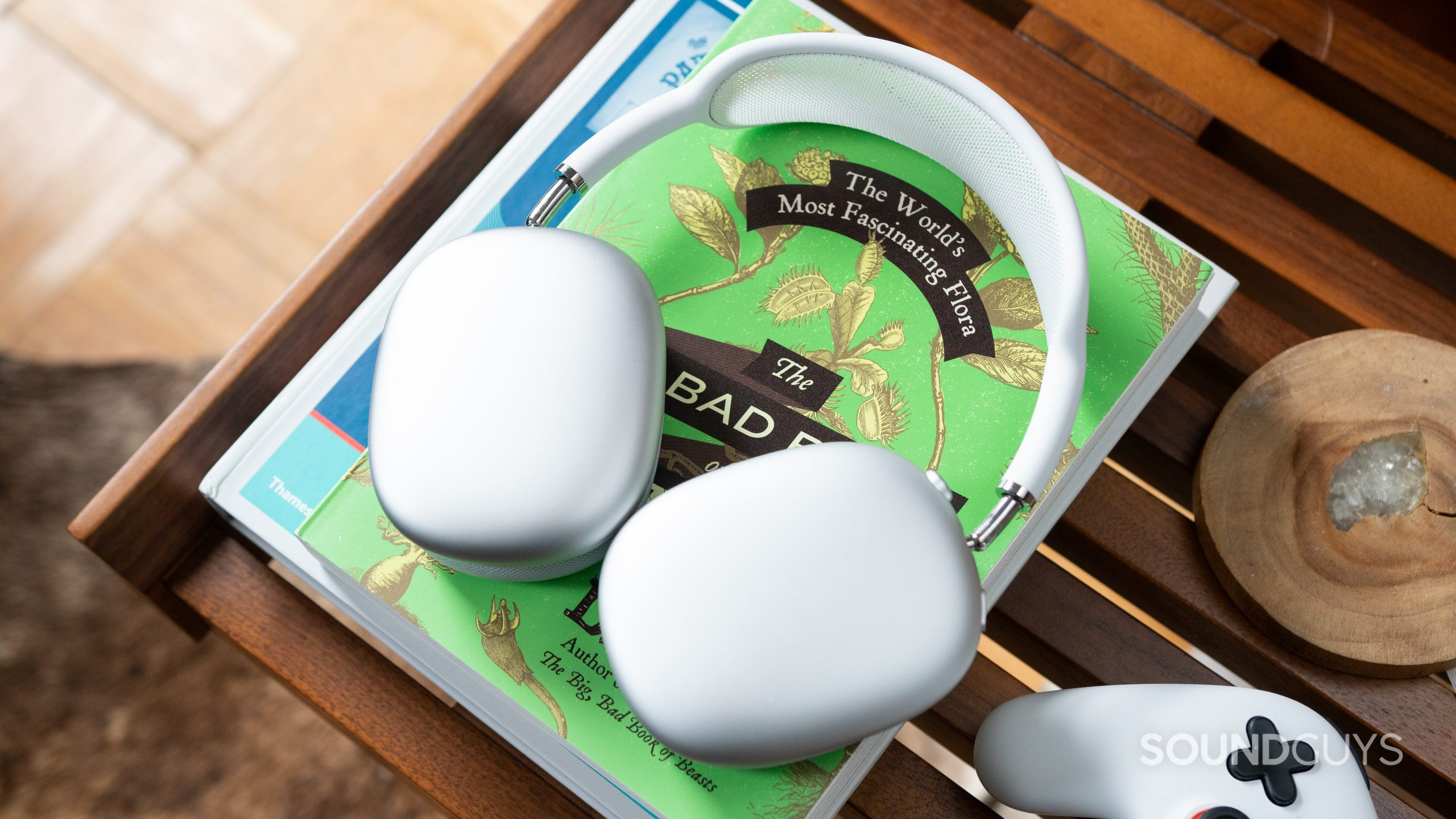 Apple AirPods Max hero shot White Apple AirPods Max on top of a green book on a coffee table.