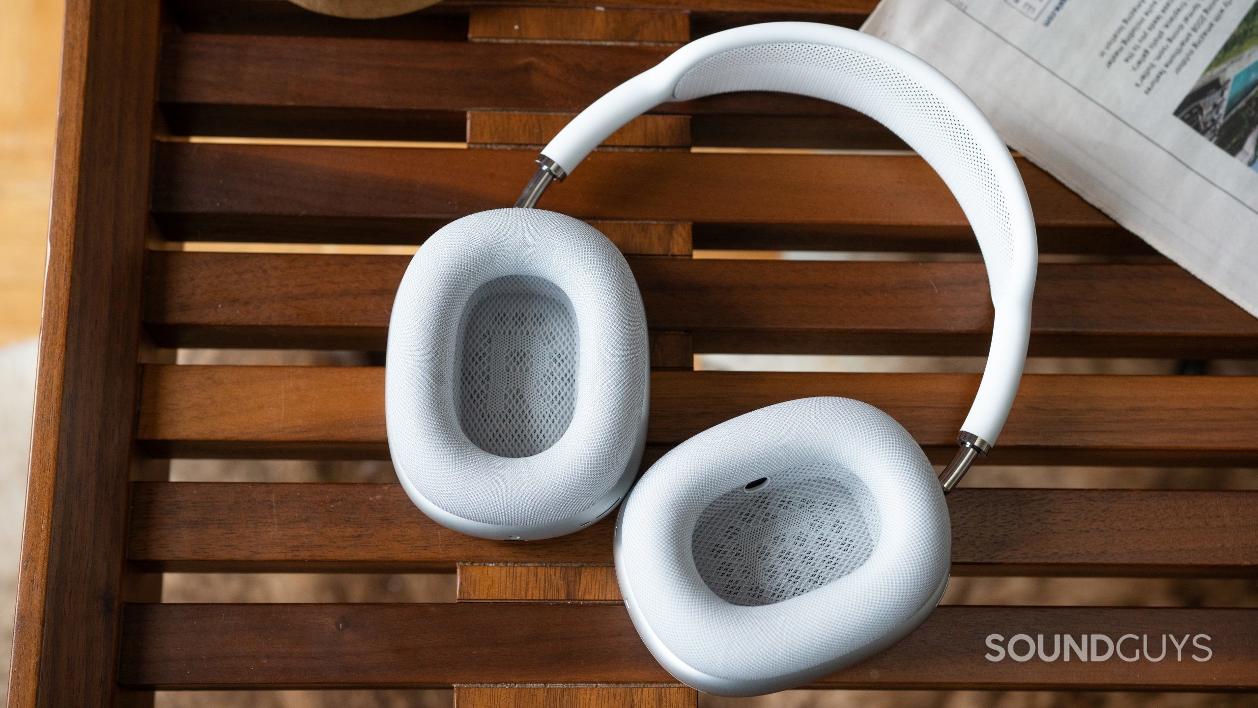 Apple AirPods Max inside ear cups. The white Apple AirPods Max lying flat so you can see inside the ear cups as they rest on a coffee table.