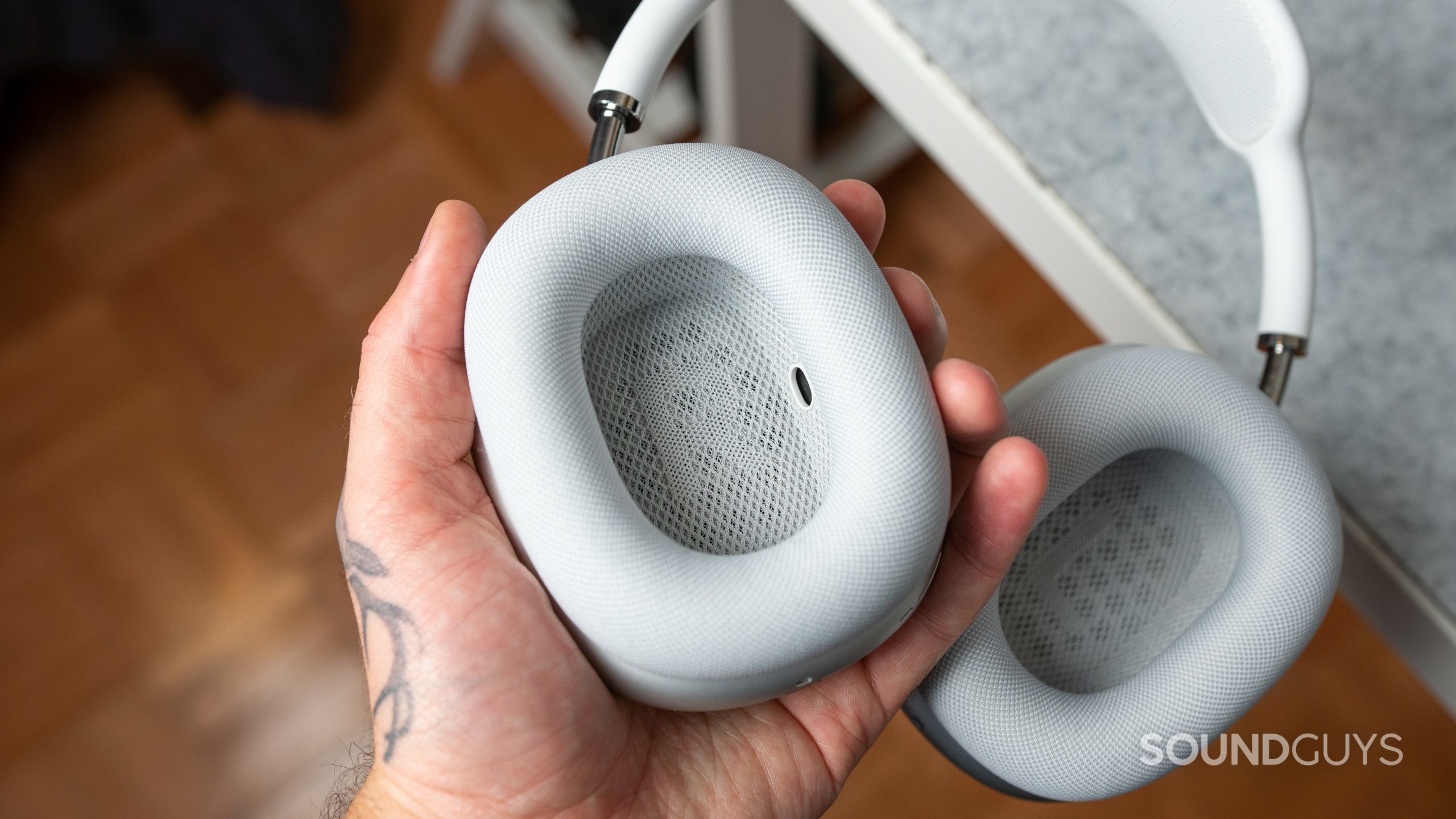 Apple AirPods Max in hand. Man holding the Apple AirPods Max over a desk.