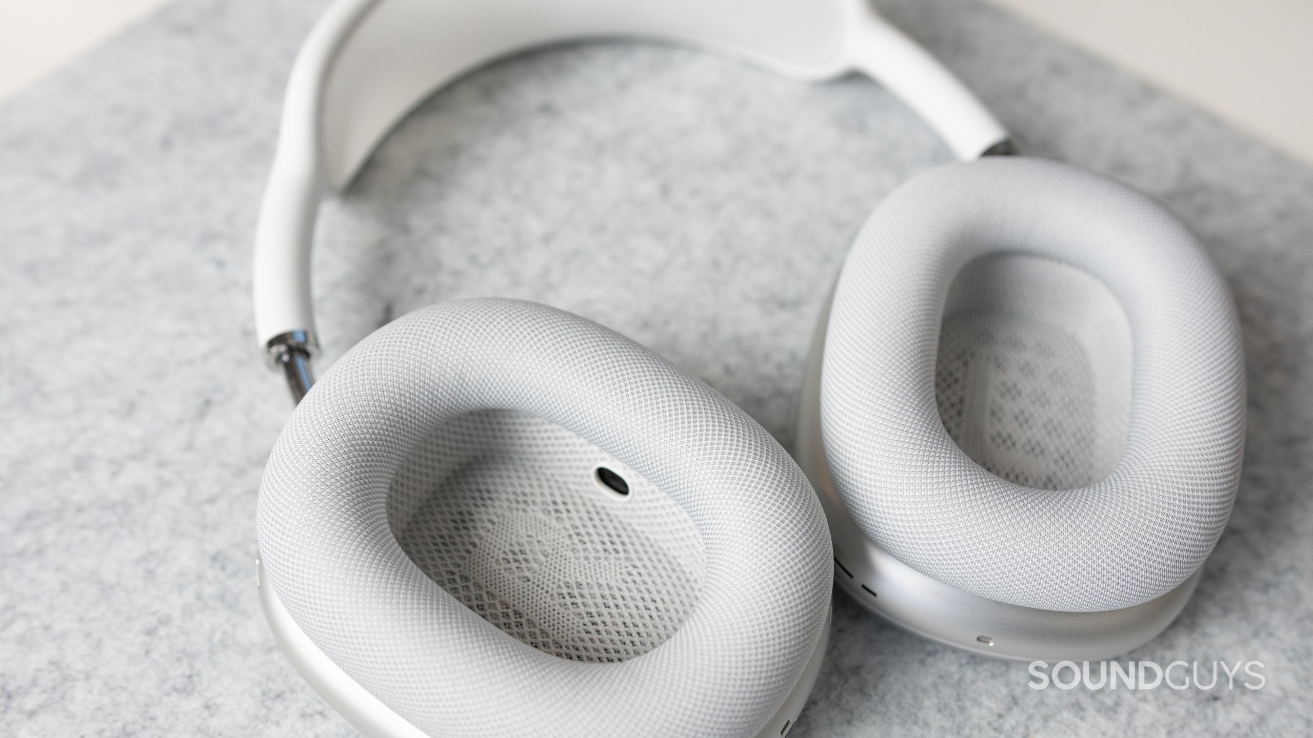 Apple AirPods Max ear cups. The Apple AirPods Max in white on a gray felt deskmat.