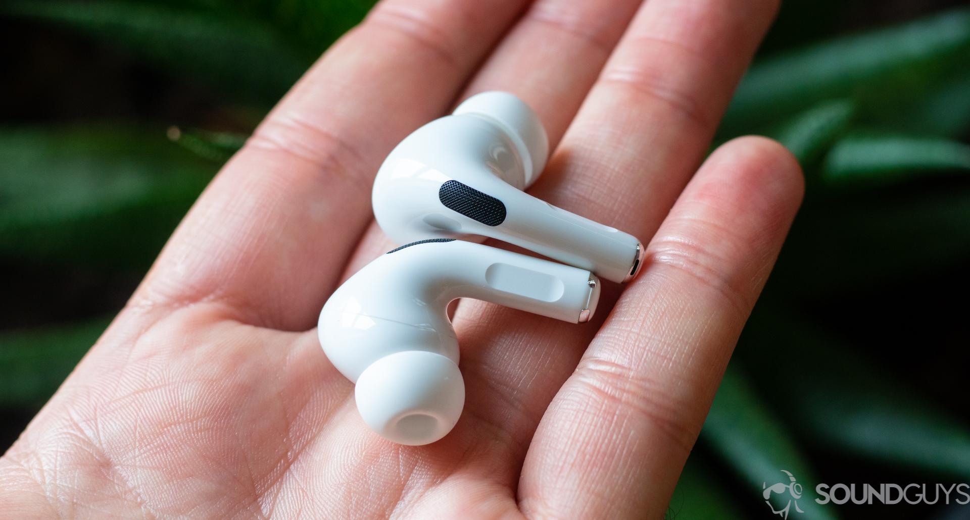 Apple AirPods Pro-12 The Apple AirPods Pro in a man's left hand against a green background.