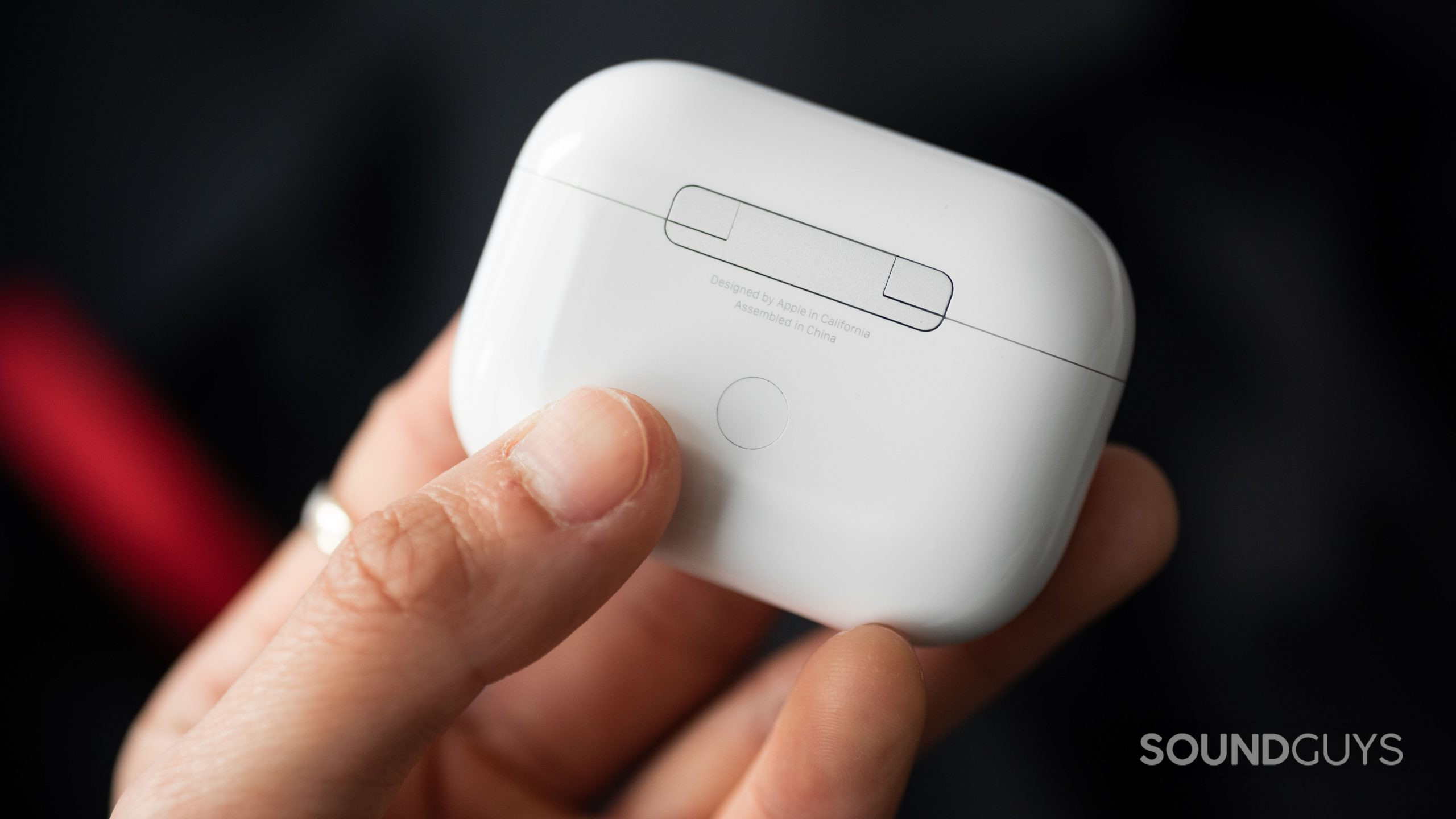 Apple AirPods Pro (2nd generation) true wireless earbuds case button hand A hand holds the Apple AirPods Pro (2nd generation) case with the pairing button in full view.
