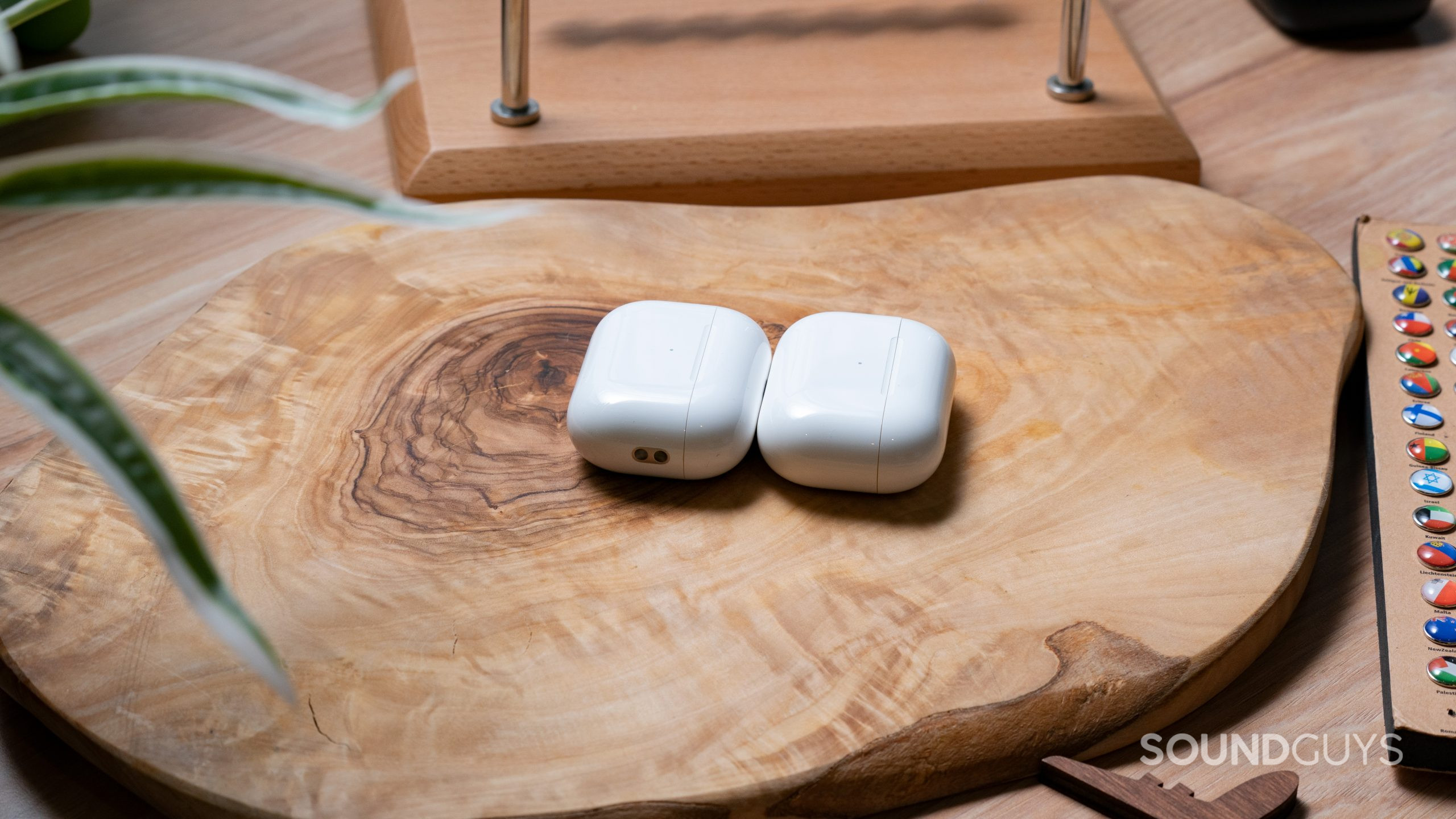 Apple Airpods Pro Gen 2 vs. Apple Airpods Pro Gen 1 Case Comparison The Apple AirPods Pro (2nd generation) case lays on a wooden surface next to the Apple AirPods Pro (1st generation) case.