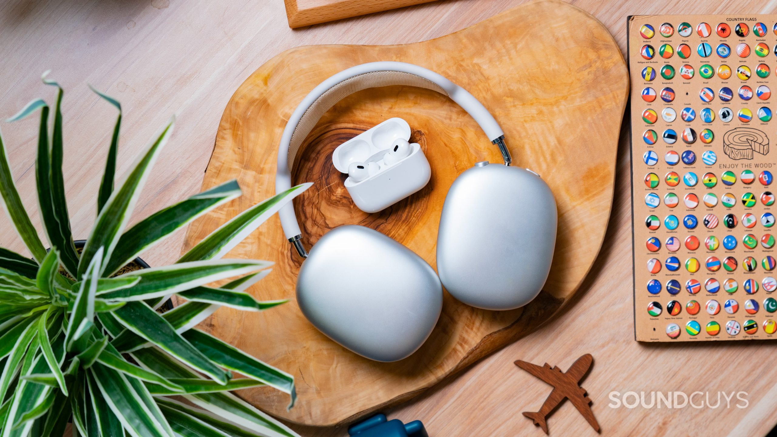 Apple Airpods Pro Gen 2 vs. Apple Airpods Pro Max Hero Image The Apple AirPods Max and Apple AirPods Pro (2nd generation) together on a wooden slab.