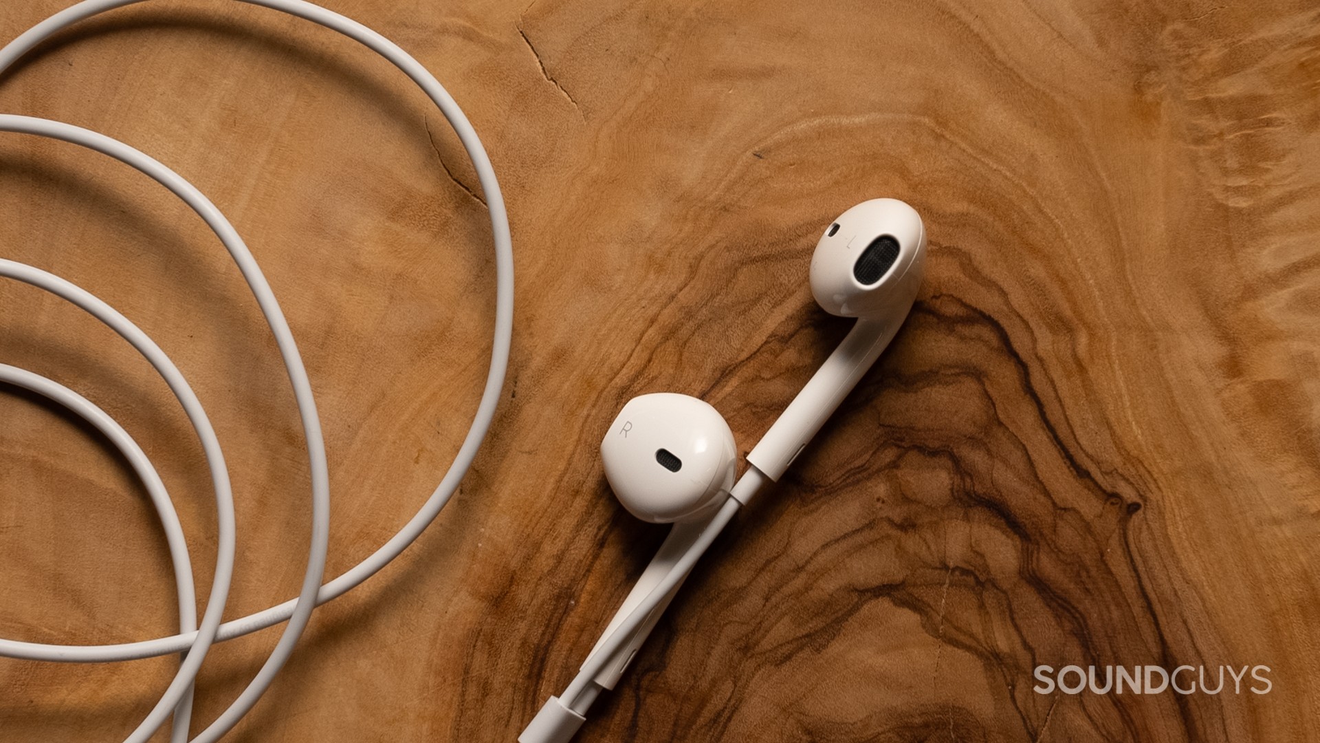 apple-earpods-buds The Apple EarPods sitting atop a piece of dark-grained wood.