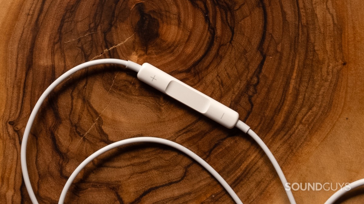 apple-earpods-controls Apple EarPods (USB-C) sit atop dark wood, with a focus on the controls.