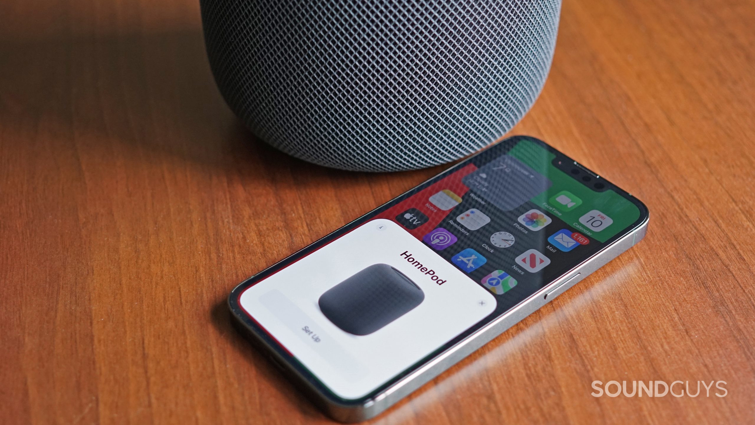 Apple-HomePod-(2nd-Generation)-iPhone-13-Pro-setup An Apple iPhone 13 Pro displays the initial setup card of the Apple HomePod (2nd generation) next to the smart speaker.