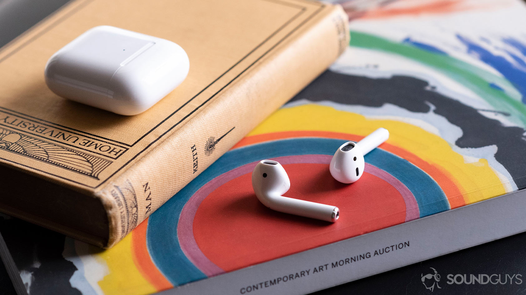 Apple new AirPods 2_earbuds case separate The Apple AirPods (2nd generation) on an arts magazine with the case above it, shut.