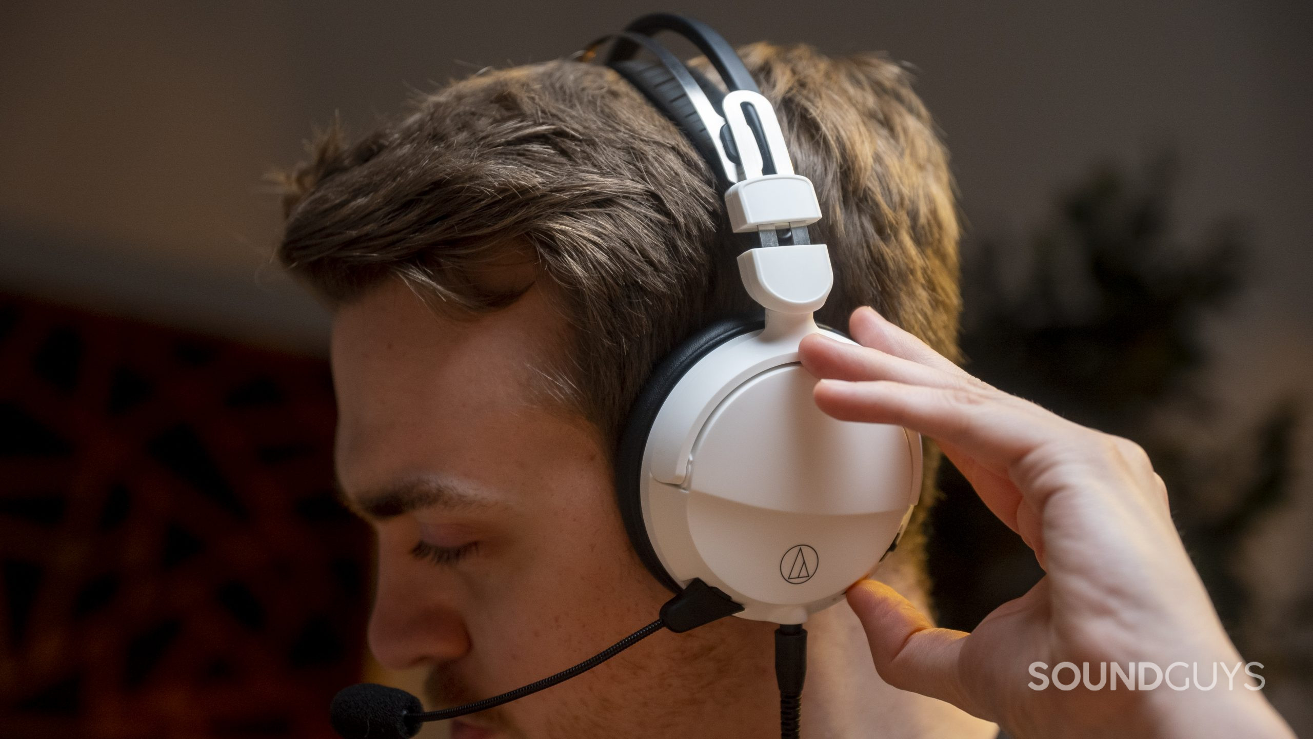 Audio-Technica ATH-GL3 gaming headset man wears controls Audio-Technica ATH-GL3 gaming headset and uses the controls on the left headphone.