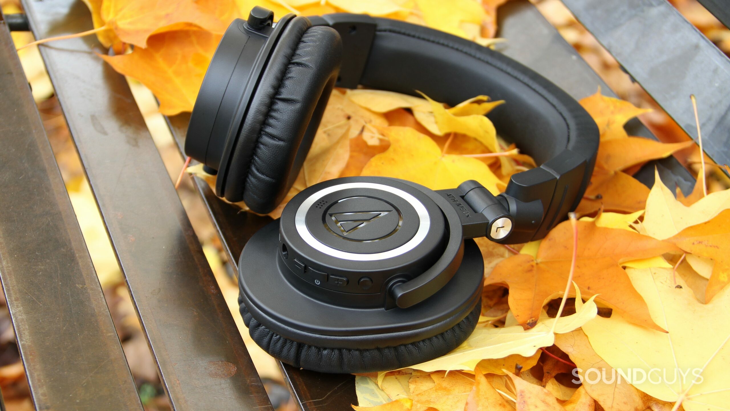 audio-technica-ath-m50xbt2-glam Audio-Technica ATH-M50xBT2 with one ear cup rotated laying flat on leaves.