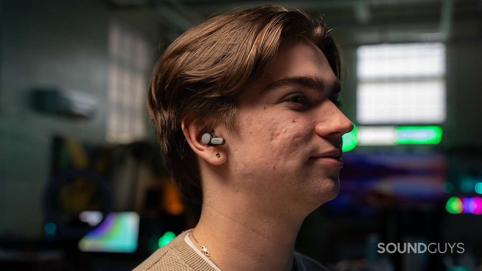 Audio Technica ATH-TWX7 on man 2 A man wearing the Audio-Technica ATH-TWX7 earbuds facing right in a dark room.
