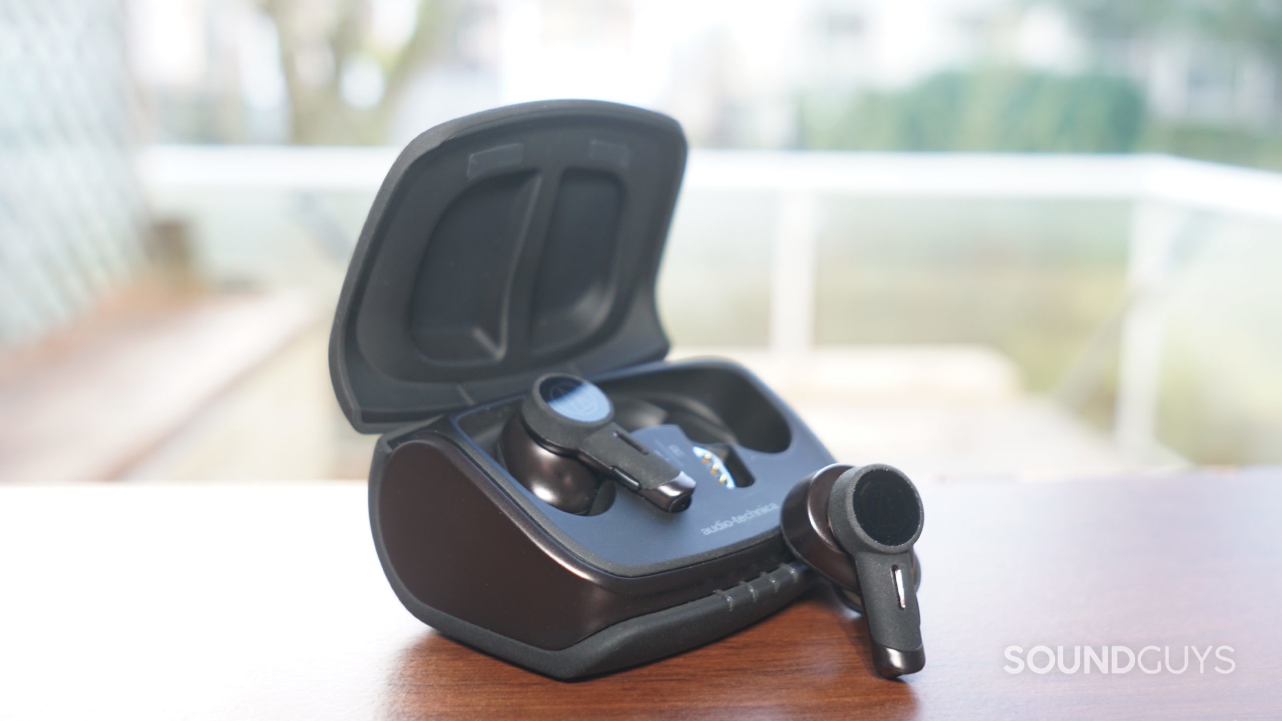 Audio-Technica-ATH-TWX9-window-case-shot The Audio-Technica ATH-TWX9 sits on a wooden surface by a window.
