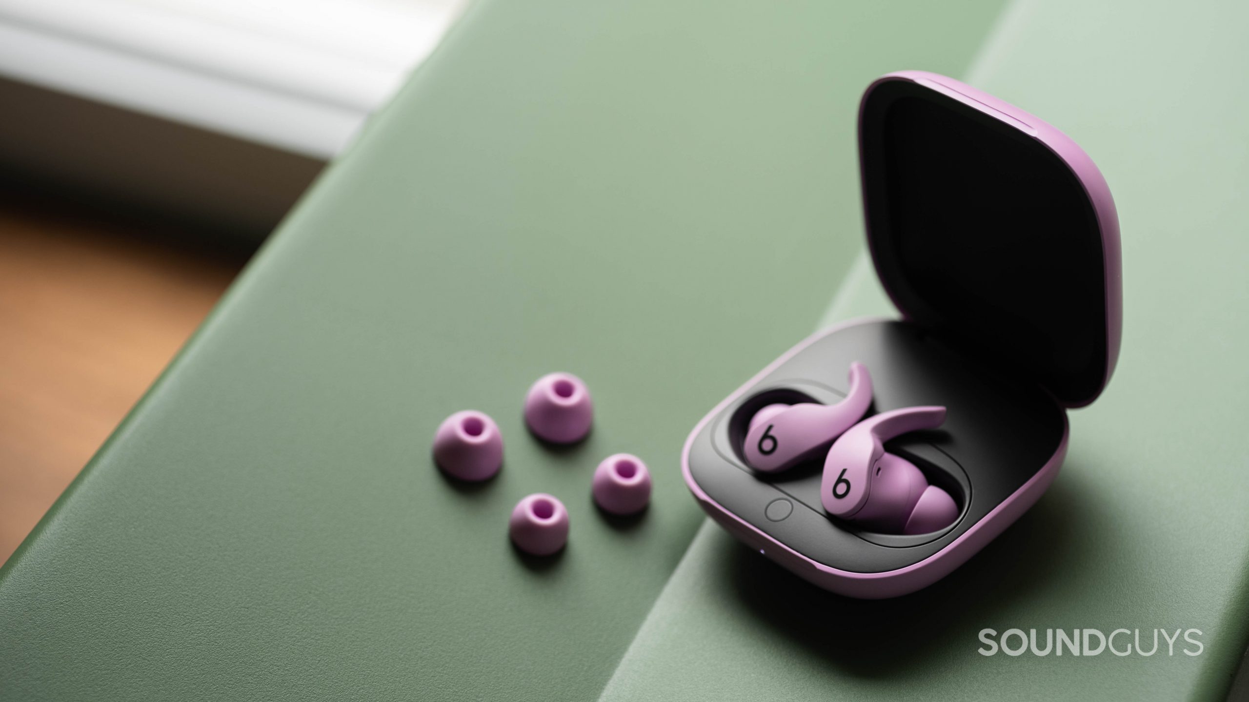 Beats Fit Pro noise canceling true wireless earbuds case ear tips The Beats Fit Pro noise canceling true wireless earbuds in the open case and next to the two extra pairs of ear tips, all of which are in the purple variant.