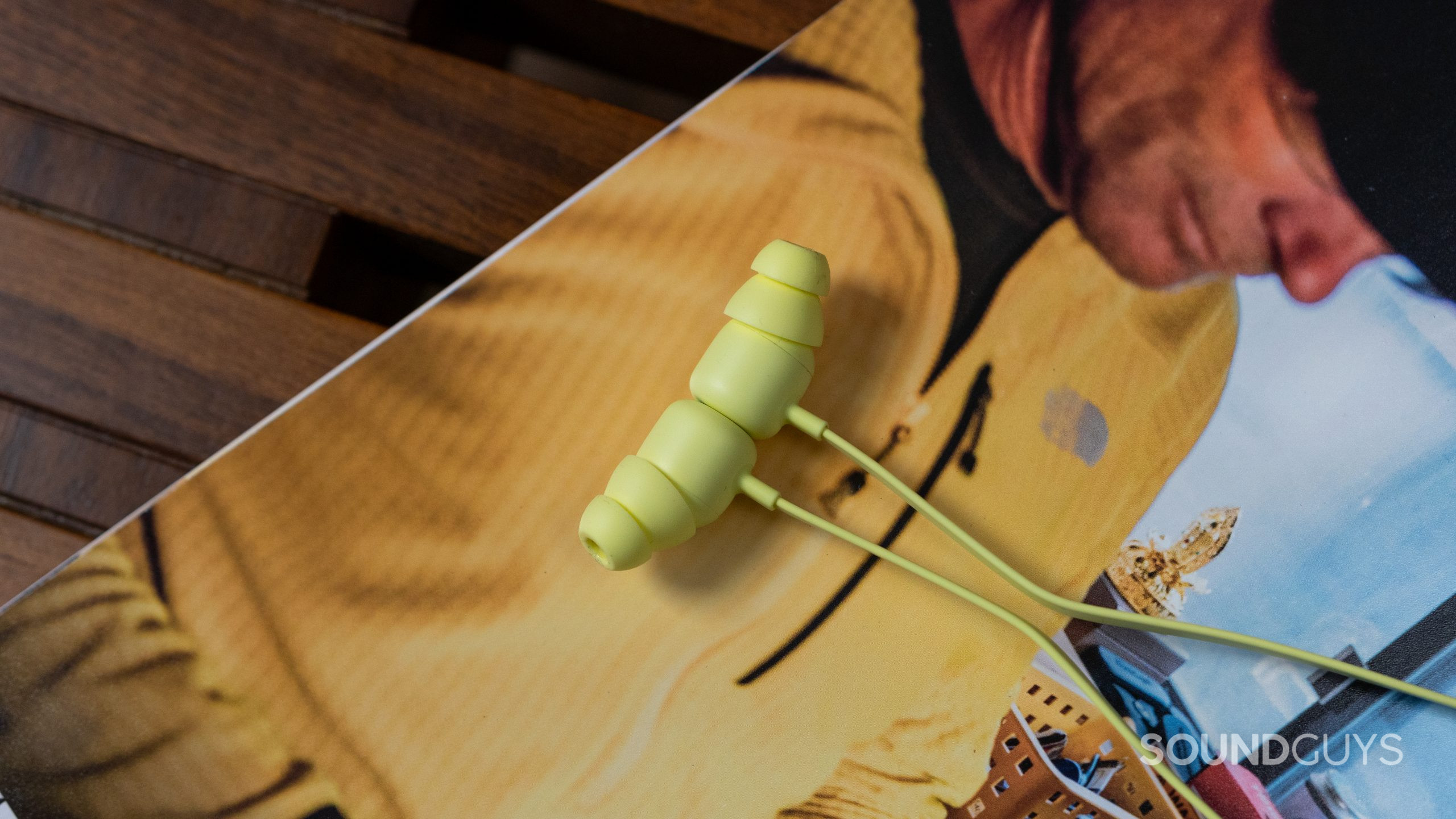Beats Flex earbuds. Beats Flex earbuds snapped together on top of a magazine.
