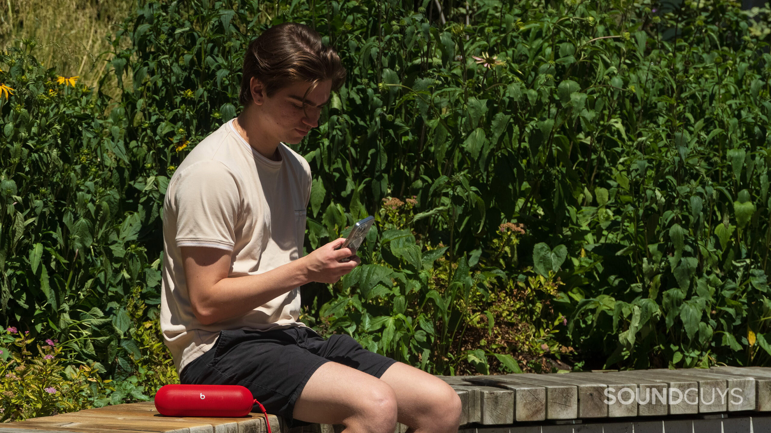 Beats Pill next to man on bench A man sitting next to a Beats Pill speaker.