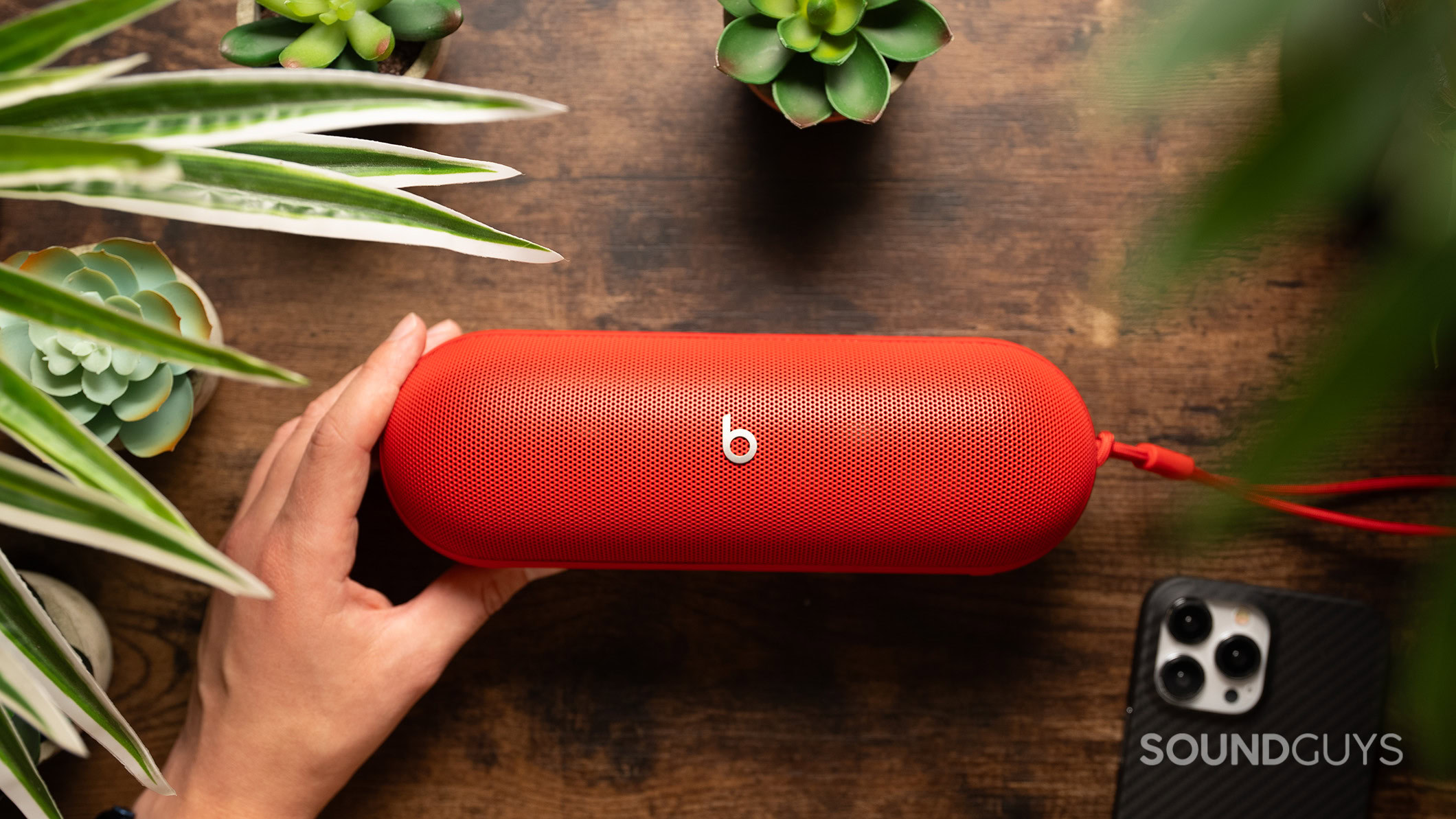 Beats Pill on a table next to plants Beats Pill on a table next to plants and a phone.