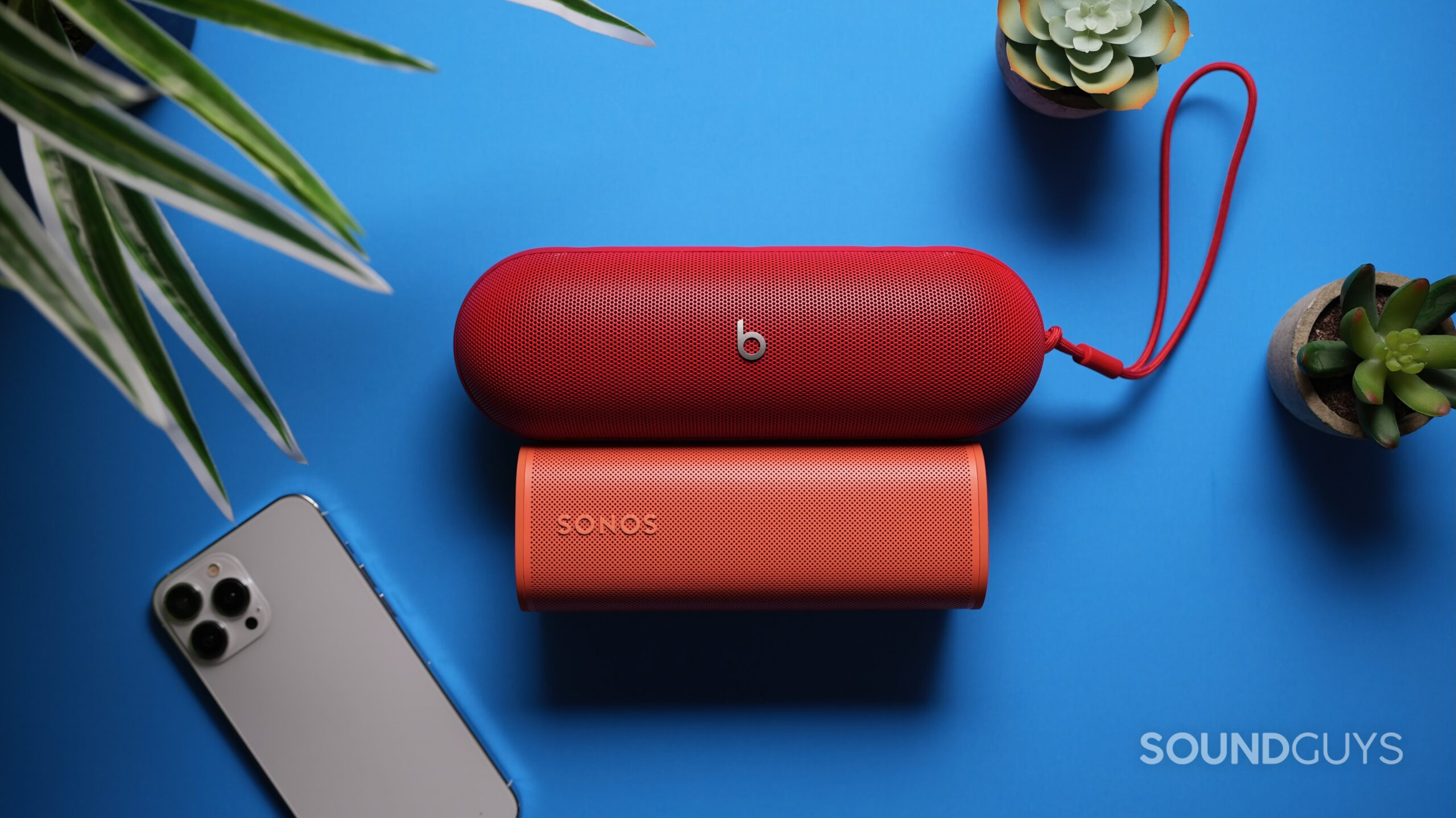 Beats Pill vs Roam 2 1 Top down shot of a Beats Pill above a Sonos Roam 2 with am iPhone 15 nearby