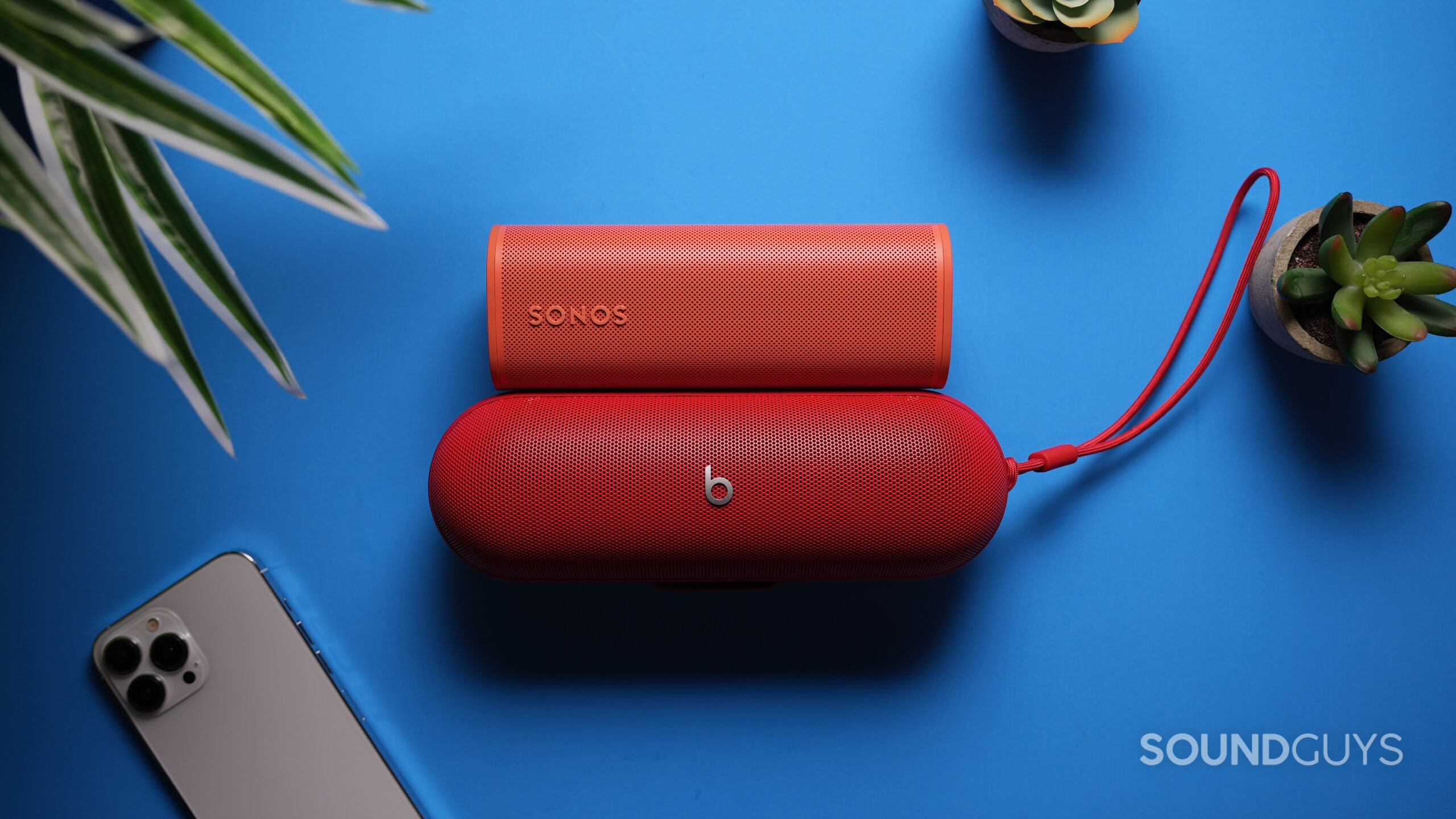 Beats Pill vs Roam 2 2 Top down shot of a a Sonos Roam above a Beats Pill with an iPhone 15 nearby