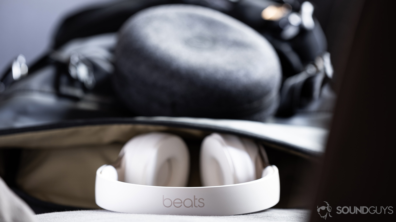 Beats Solo Pro-noise canceling headphones headband logo backpack A photo of the Beats Solo Pro on-ear noise canceling headphones headband emerging from a backpack with the cloth carrying pouch hooked to it.