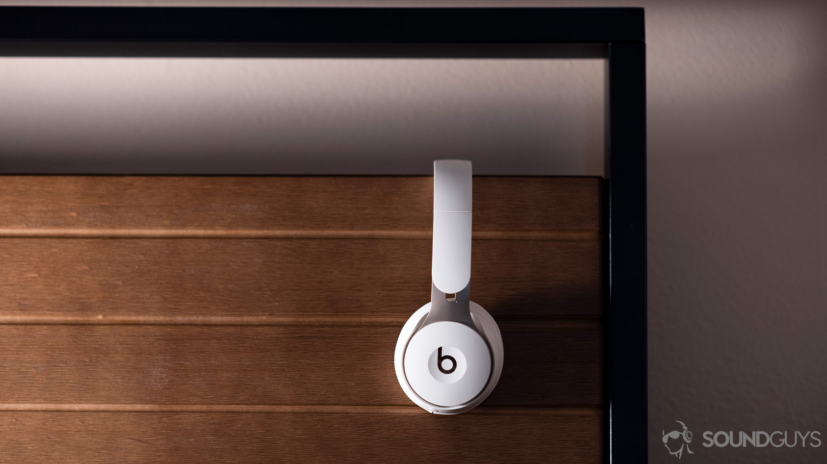 Beats Solo Pro-noise canceling headphones profile wood background The Beats Solo Pro on-ear noise canceling headphones in profile against a wooden background.