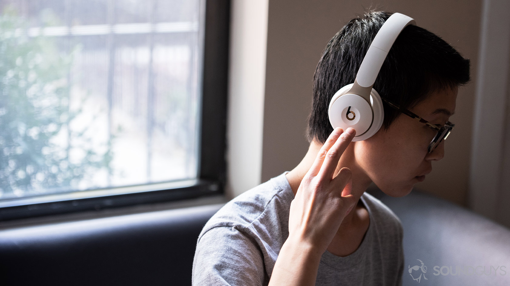 Beats Solo Pro-noise canceling headphones woman touch controls gesture A photo of the Beats Solo Pro on-ear noise canceling headphones being worn by a woman using the right ear cup controls.