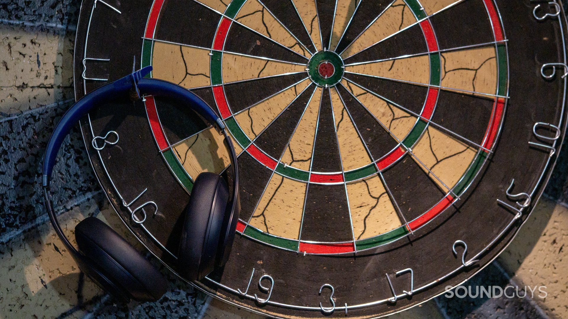 beats-studio-pro-miss-the-mark The Beats Studio Pro hanging from a dart, thrown aside of the dartboard.
