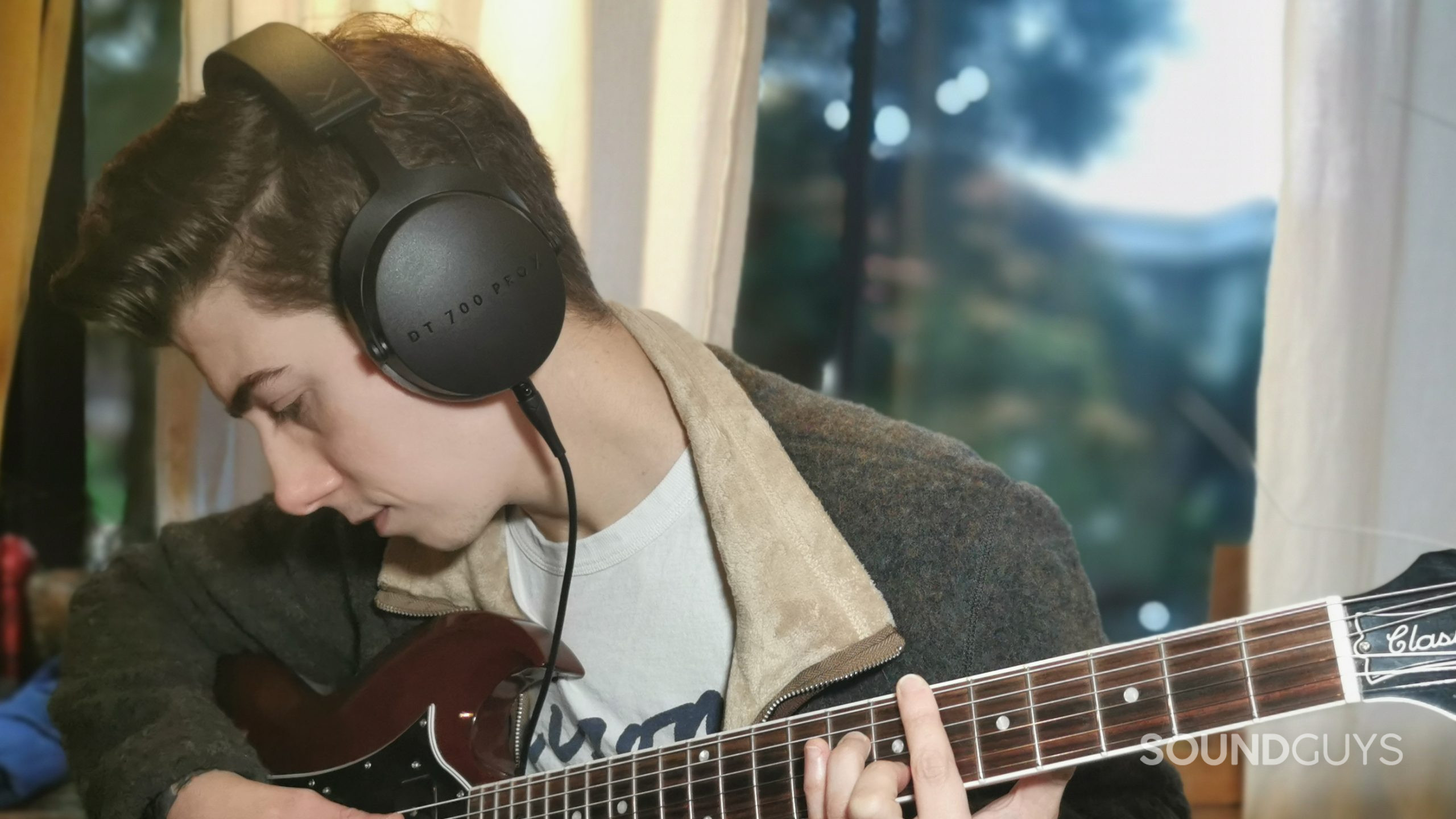 beyerdynamic-dt-700-pro-x-on-ears A man plays guitar wearing the Beyerdynamic DT 700 Pro X.