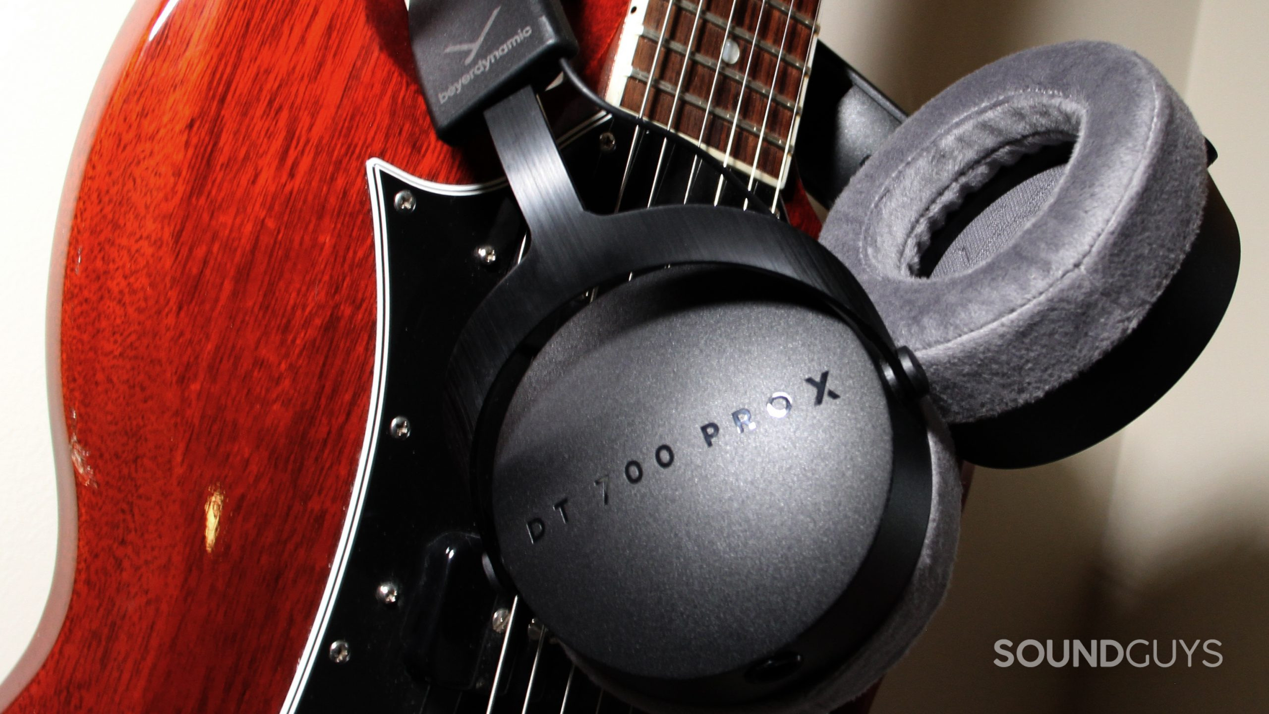 beyerdynamic-dt-700-pro-x--padding Around the neck of a red guitar the Beyerdynamic DT 700 Pro X is slung over, showing the ear cups.