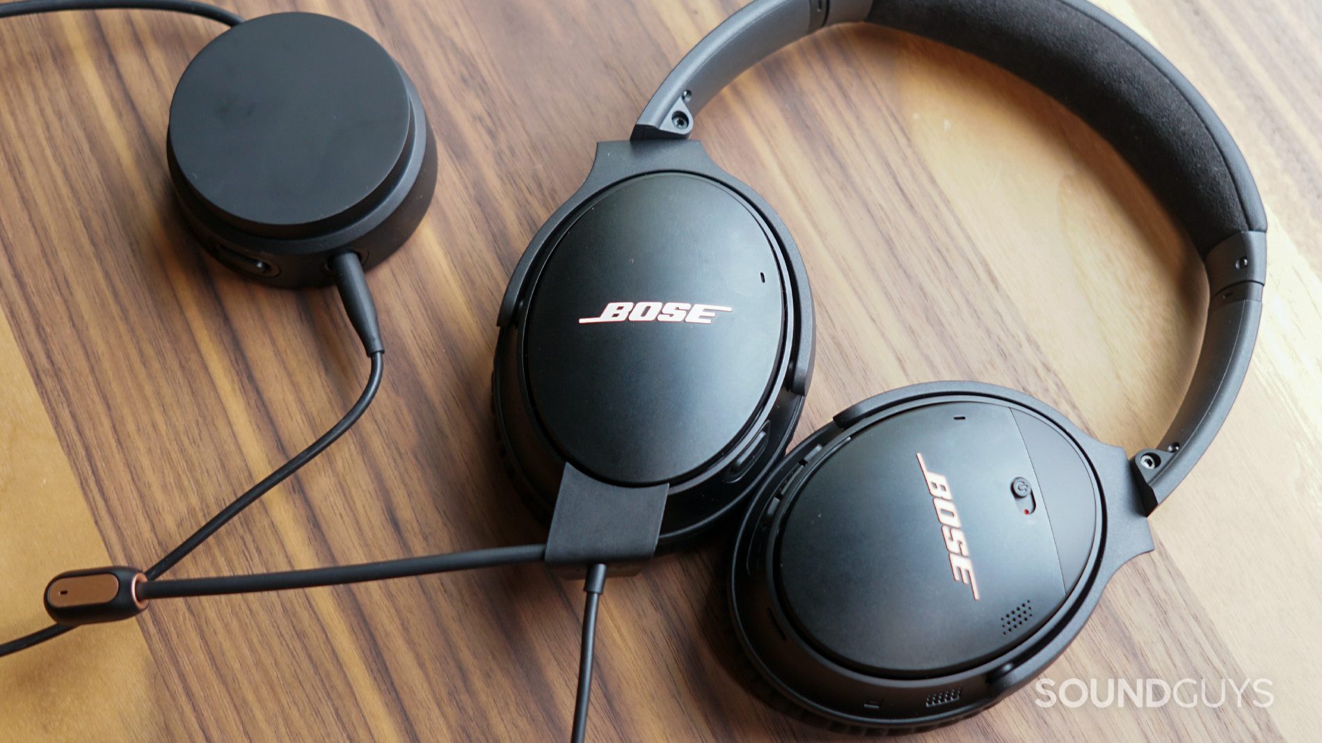 Bose QuietComfort 35 II Gaming Headset flat window shot The Bose QuietComfort lays flat on a wooden table plugged into its volume dial.
