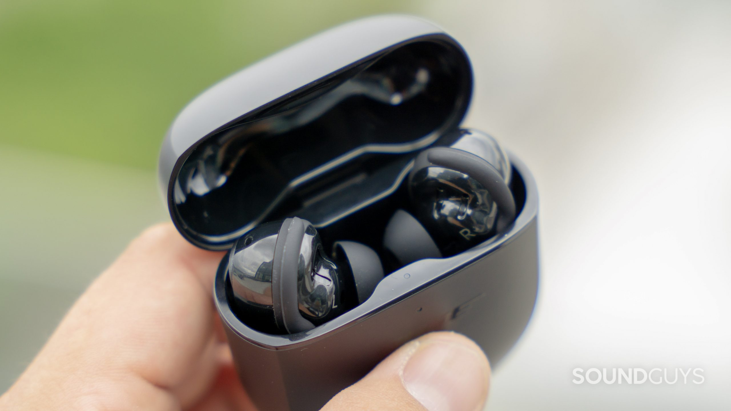Bose QuietComfort Earbuds II true wireless noise canceling case earbuds aerial An angled view of a hand as it holds the Bose QuietComfort Earbuds II case with the lid flipped up to show the earphones.