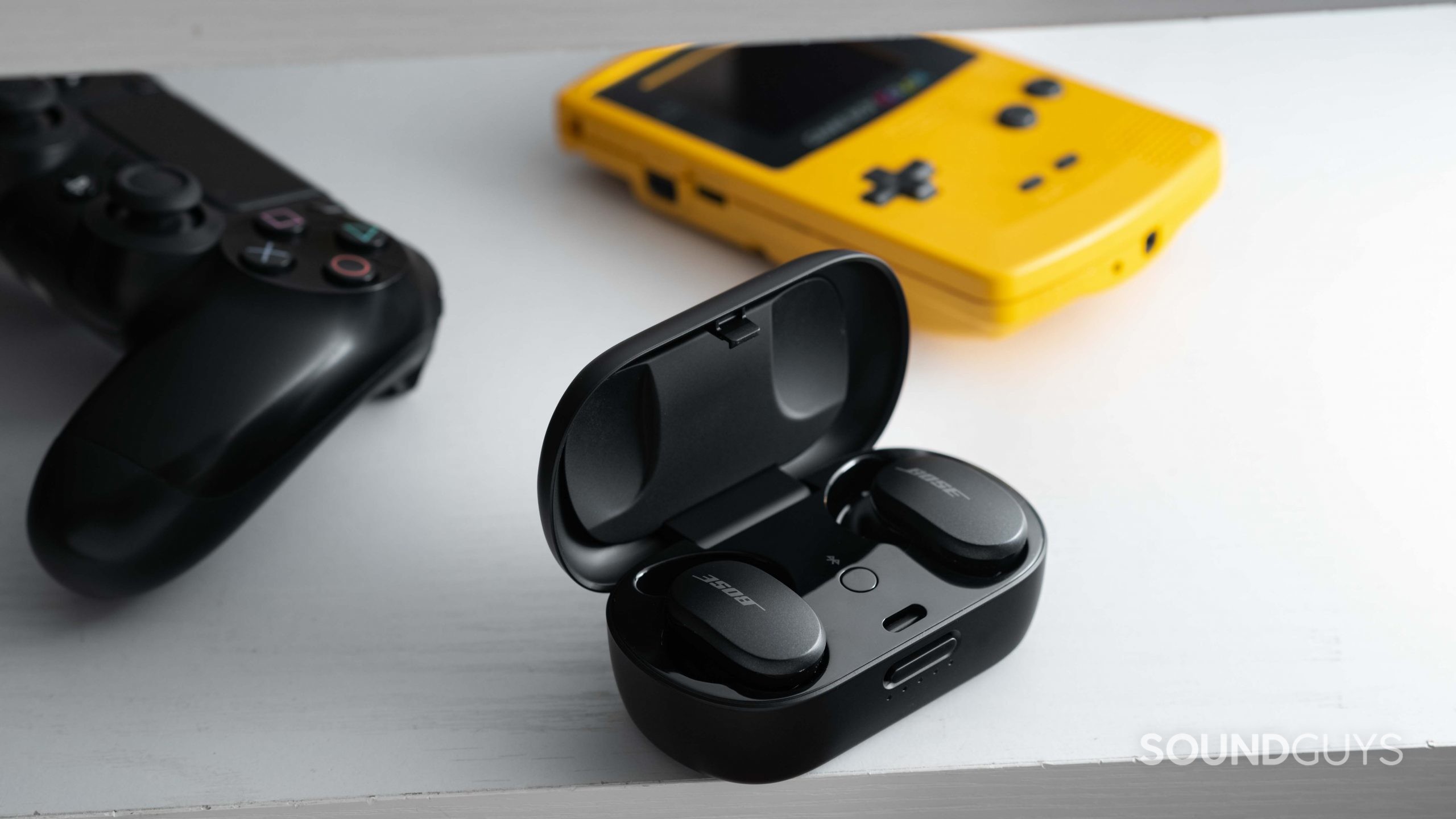 Bose QuietComfort Earbuds noise canceling true wireless-1 The Bose QuietComfort Earbuds noise canceling true wireless earbuds in the USB-C charging case next to a Gameboy Color and PlayStation 4 controller.