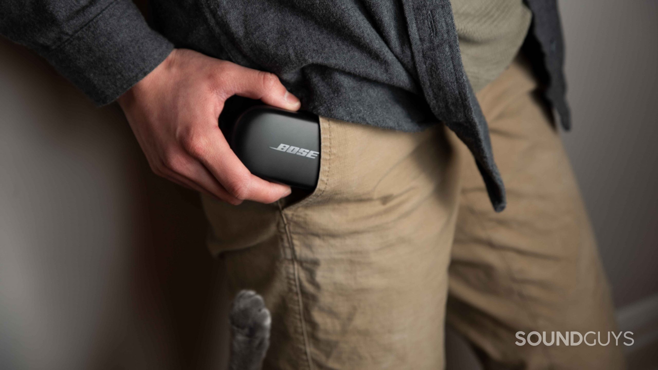 Bose QuietComfort Earbuds noise canceling true wireless-8 A cat paw reaches for the Bose QuietComfort Earbuds case as a woman inserts it into her pants pocket.