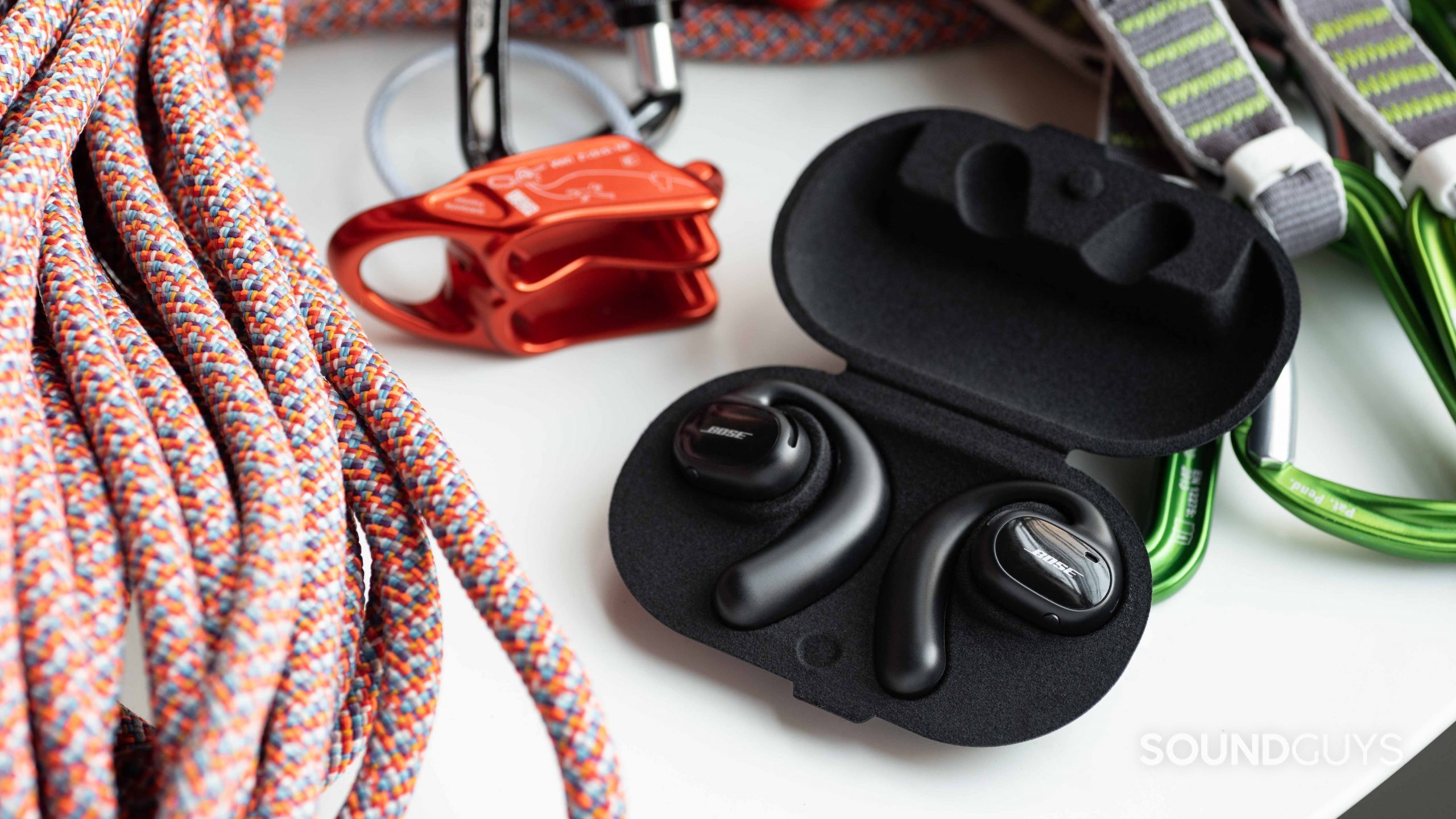 Bose Sport Open Earbuds-1 The Bose Sport Open Earbuds in the open carrying case next to a climbing rope and belay device.