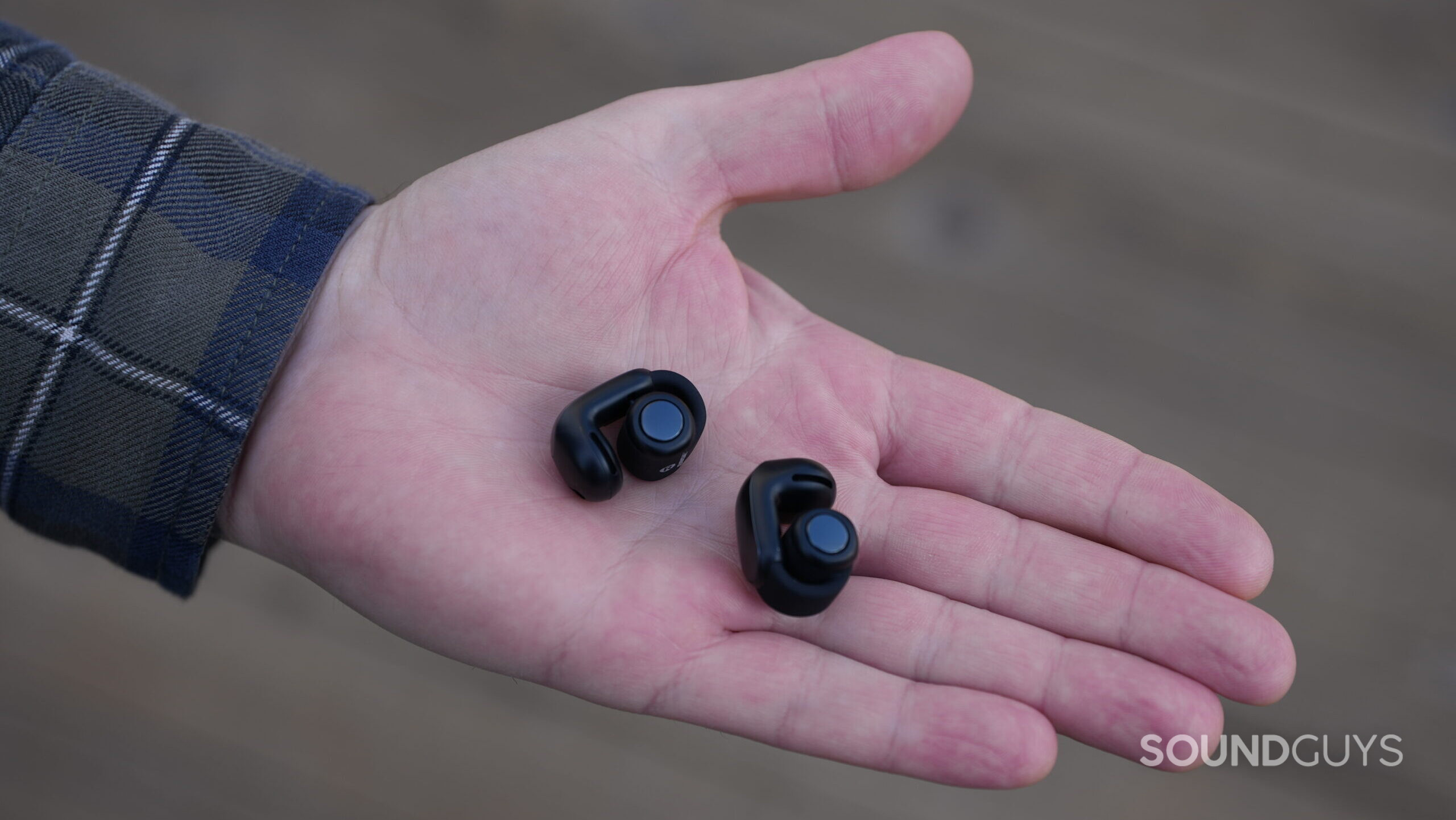 Bose UOE Hand Outside A photo of the Bose Ultimate Open Earbuds resting on an open hand