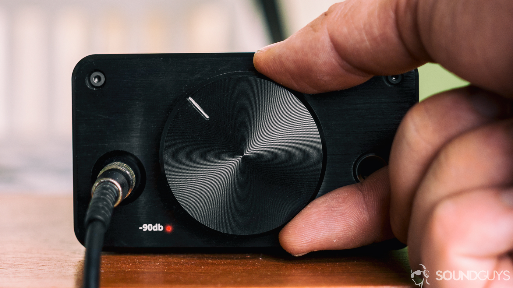 do-you-need-an-amp-hero Different driver types: A photo of a hand turning up the knob of a headphone amplifier