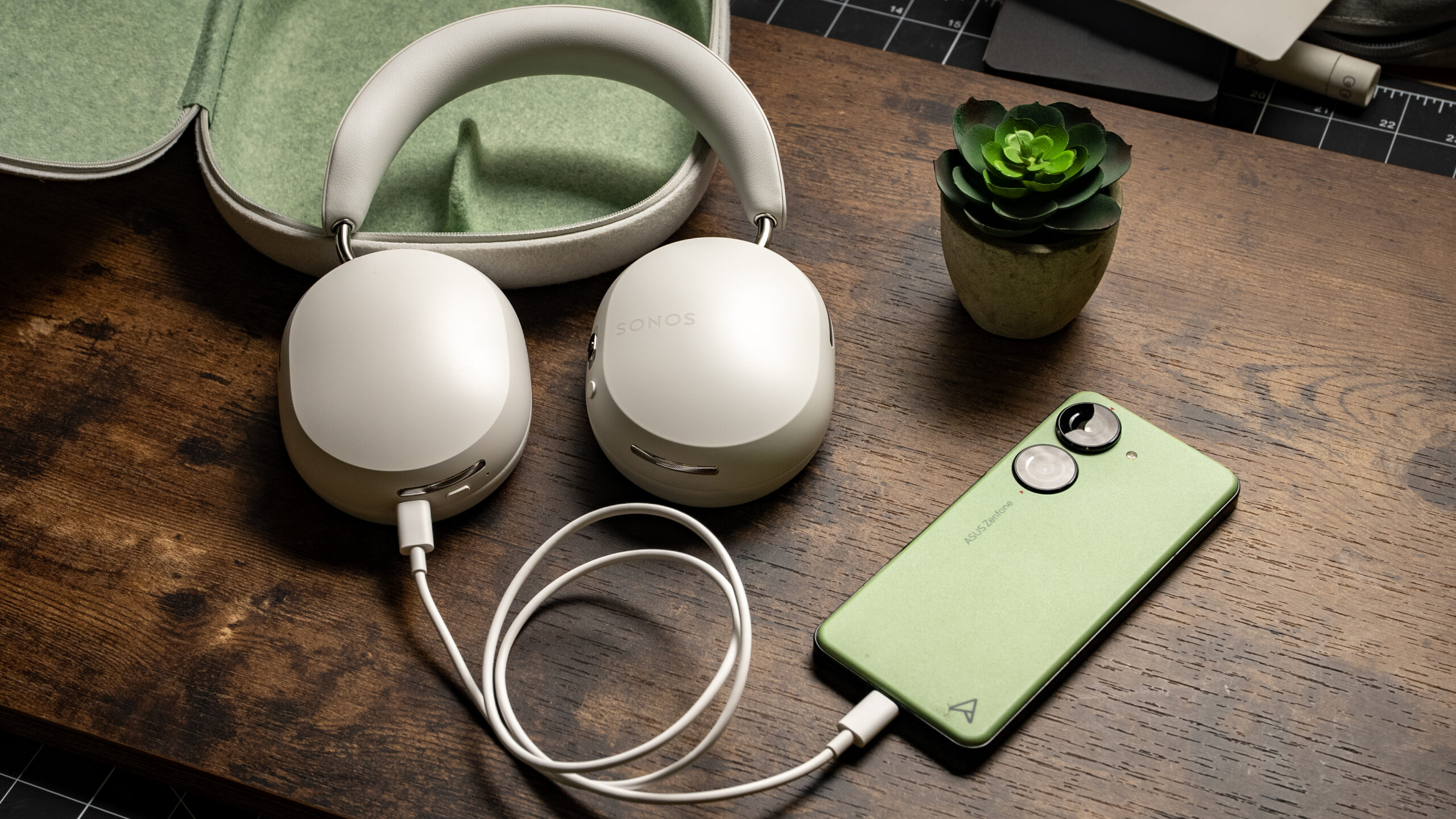 Sonos Ace headphones connected to Android phone USB-C A photo of the Sonos Ace headphones placed against its carrying case conncted to an Android smartphone using a USB-C cable