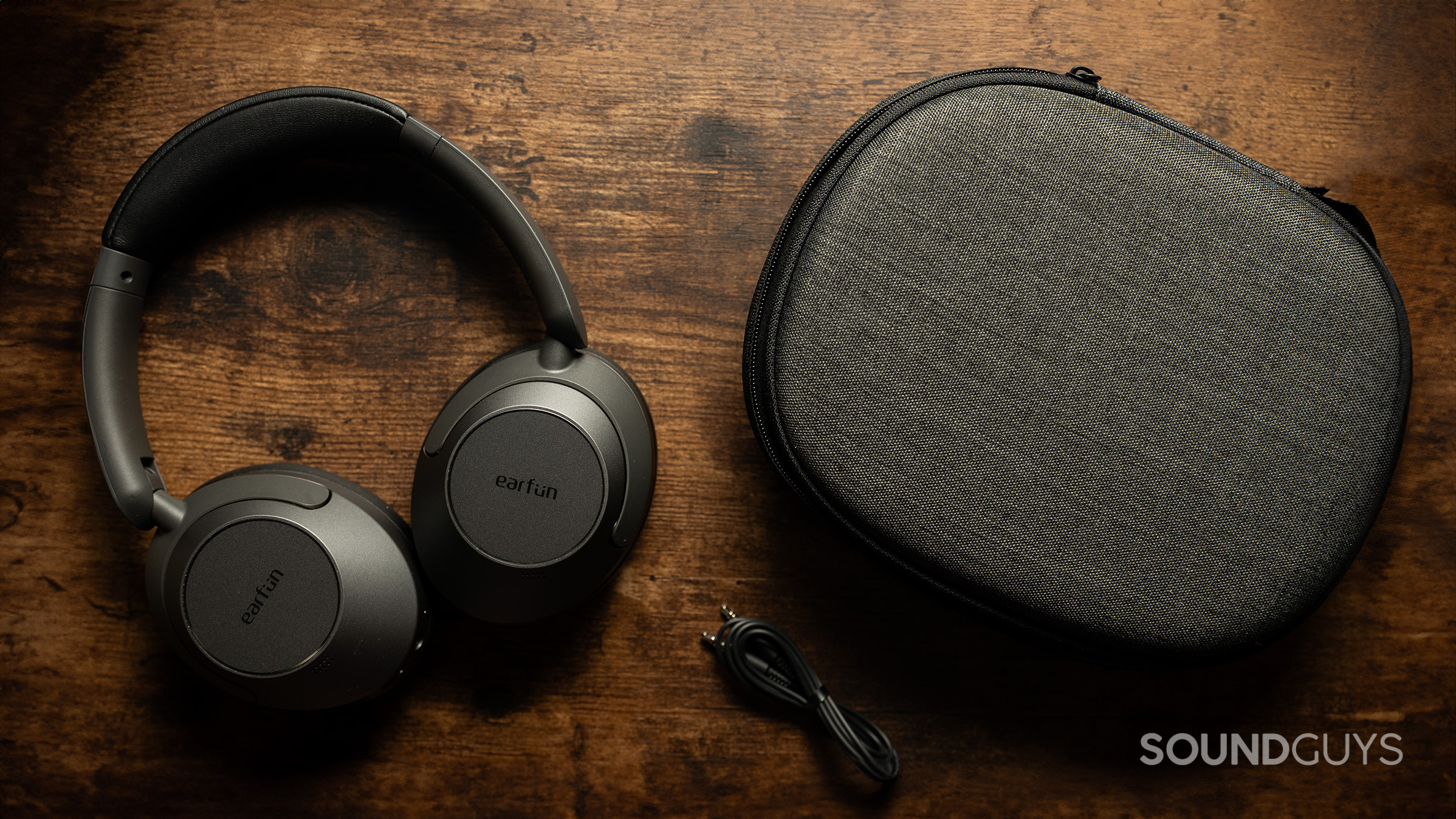 EarFun Wave Pro case 2 The EarFun Wave Pro headphones next to an audio cable and headphone case.