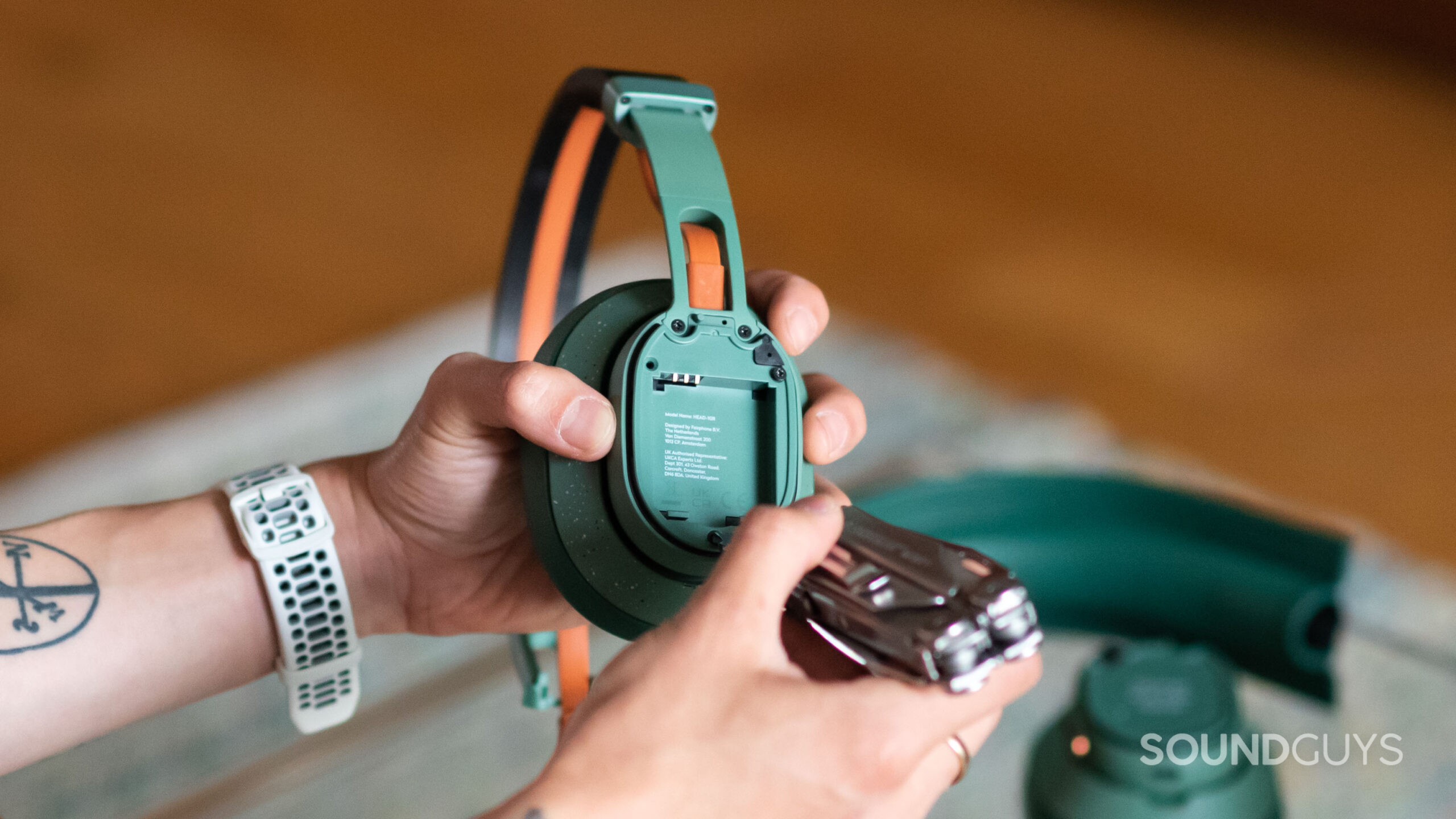 Fairphone Fairbuds XL hands repairable headphones-2 A hand unscrews the FairBuds XL.