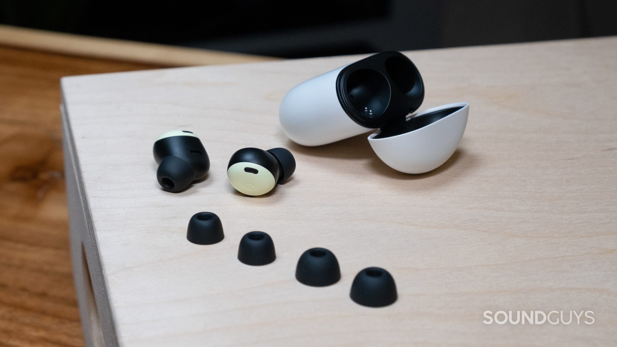 google-pixel-buds-accessories On a wood surface the Google Pixel Buds Pro case is open with the buds out, and the two spare sets of ear tips.