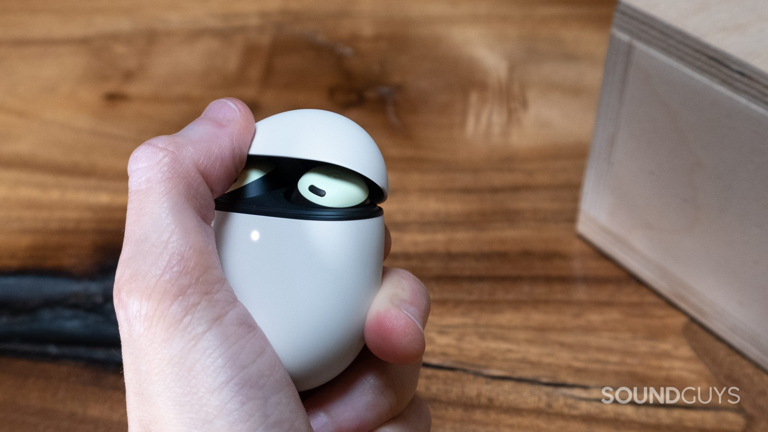 google-pixel-buds-push-open A hand holds the Google Pixel Buds Pro and is in the process of flipping up the lid with a thumb.