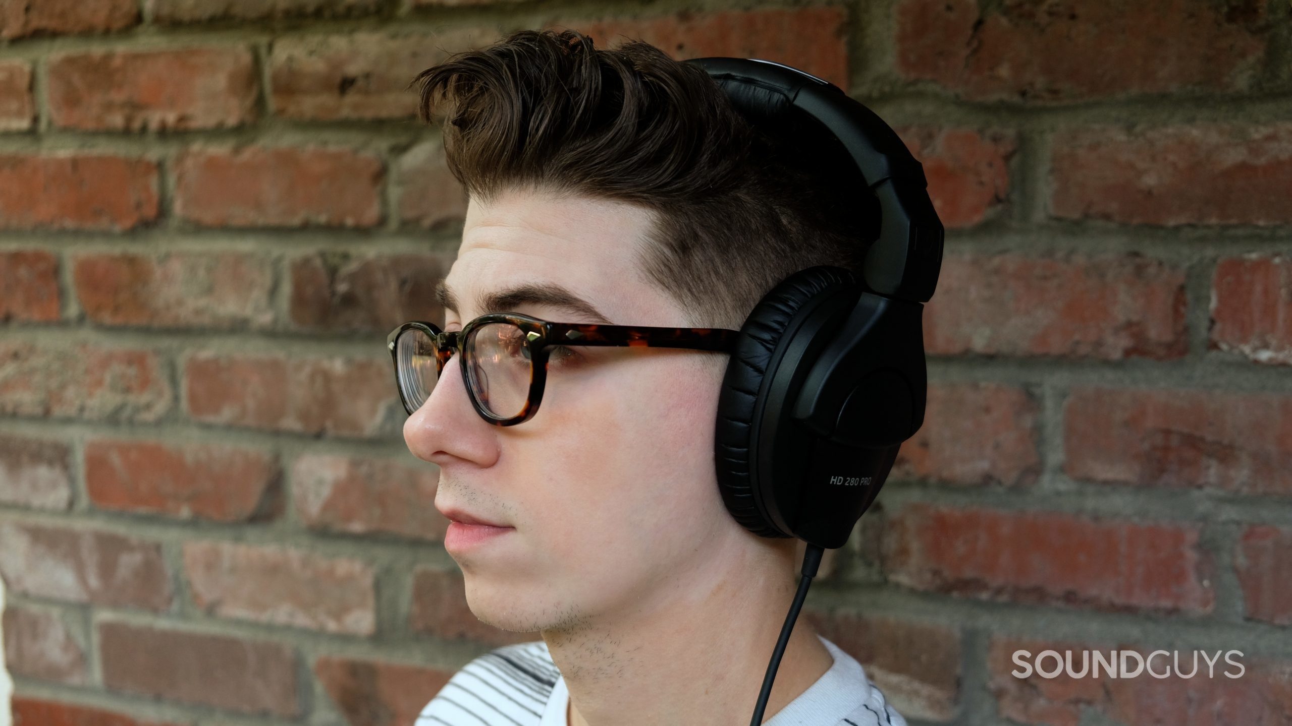 Sennheiser hd 280 pro headshot 01 A man wears the Sennheiser HD 280 Pro studio headphones in front of a brick wall.