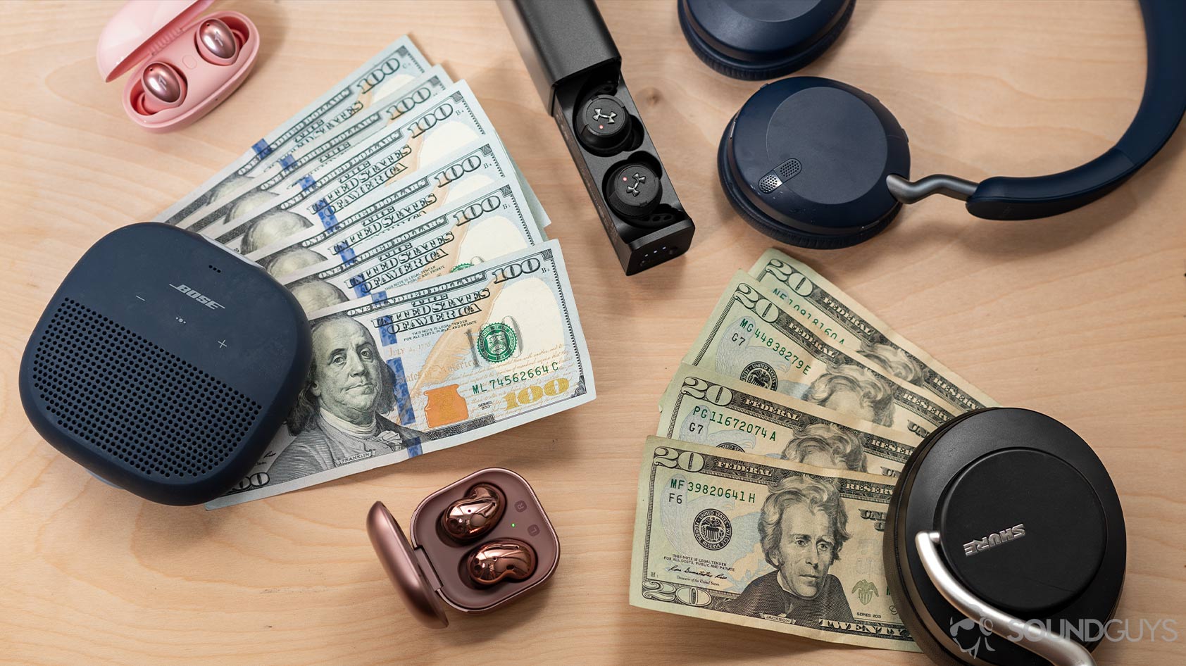 headphone data collection-e Money surrounded by wireless audio products like the Bose SoundLink Micro speaker, Samsung Galaxy Buds Live, 1More Colorbuds, Jabra Elite 45h, JBL True Wireless Flash X, and Shure AONIC 50.
