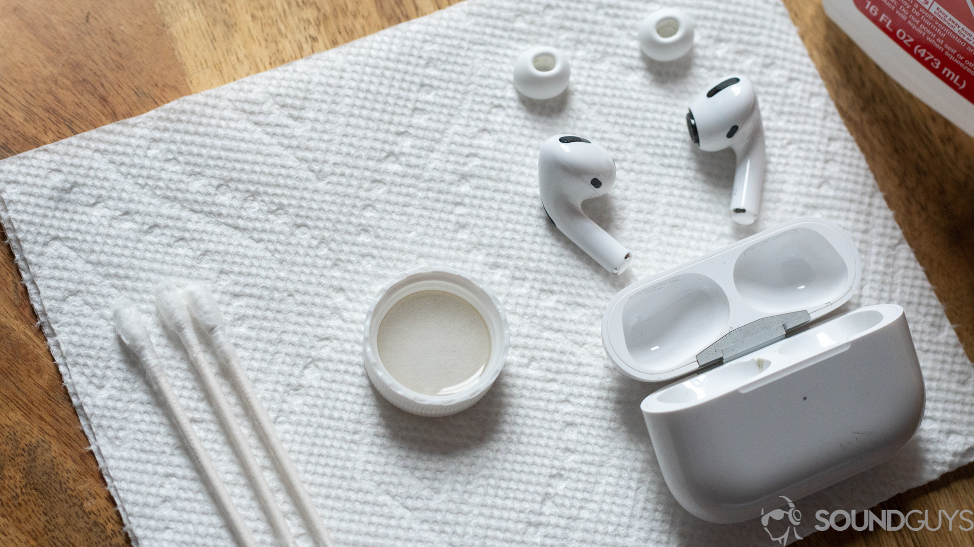 How to clean your AirPods Pro-3 A photo of the AirPods Pro with Q-tips, alcohol, and the bottle cap placed onto paper towels.